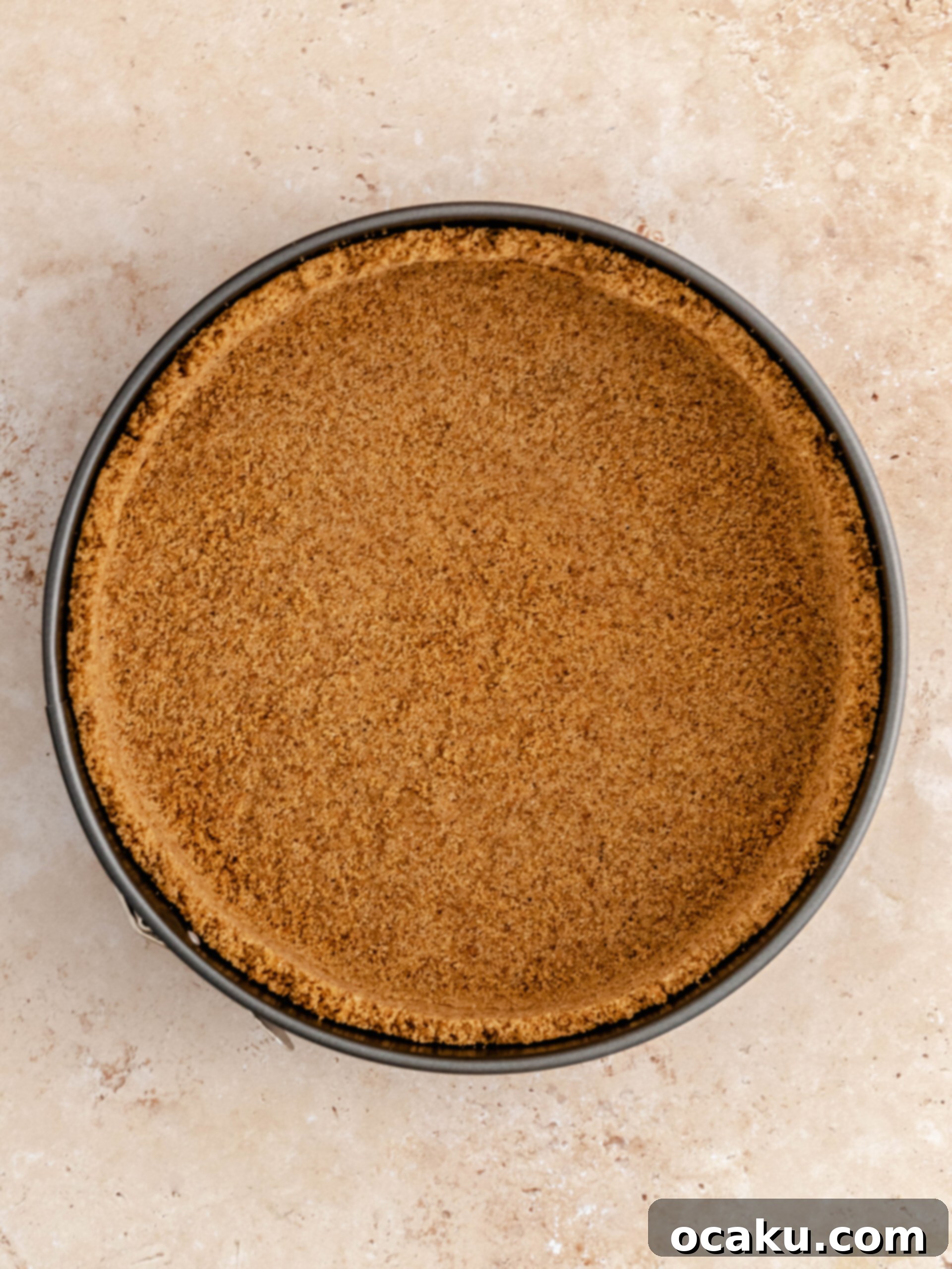 Cookie crust being pressed into a springform pan for apple crumble cheesecake.