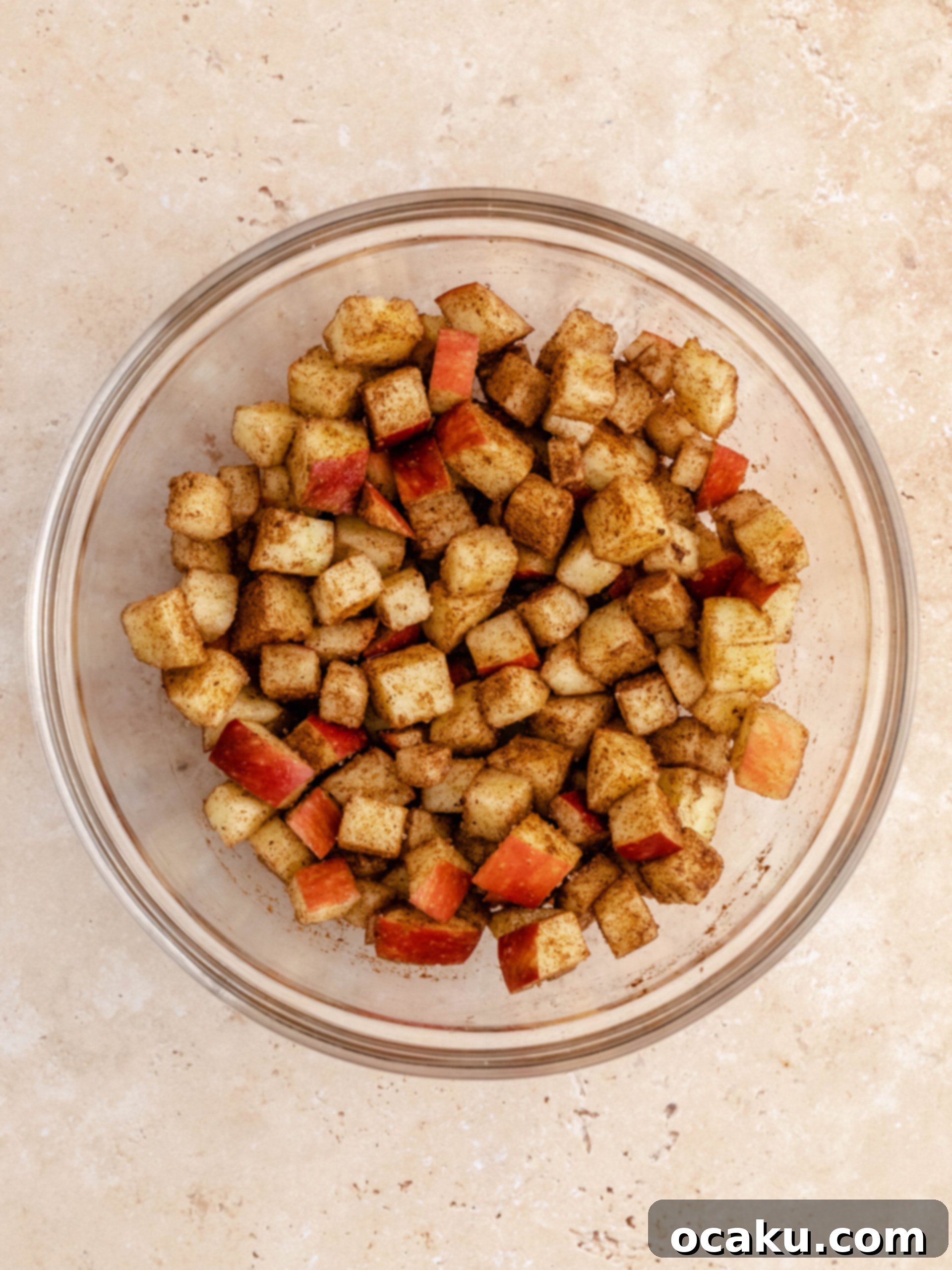 Freshly diced apples coated in cinnamon and granulated sugar, ready for the apple crumble cheesecake.