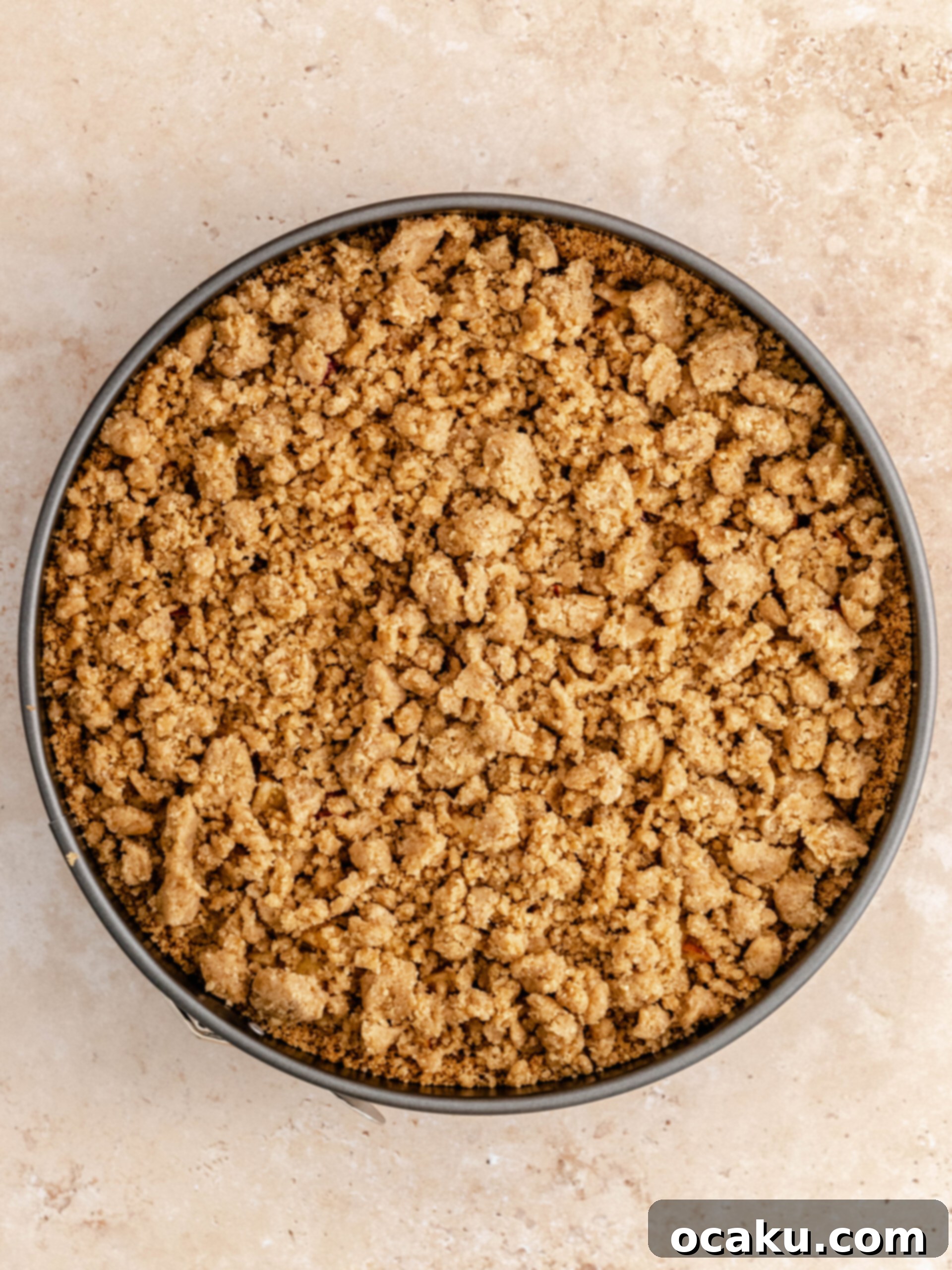 Generous layer of crunchy streusel crumble sprinkled over the cinnamon apples on the cheesecake.