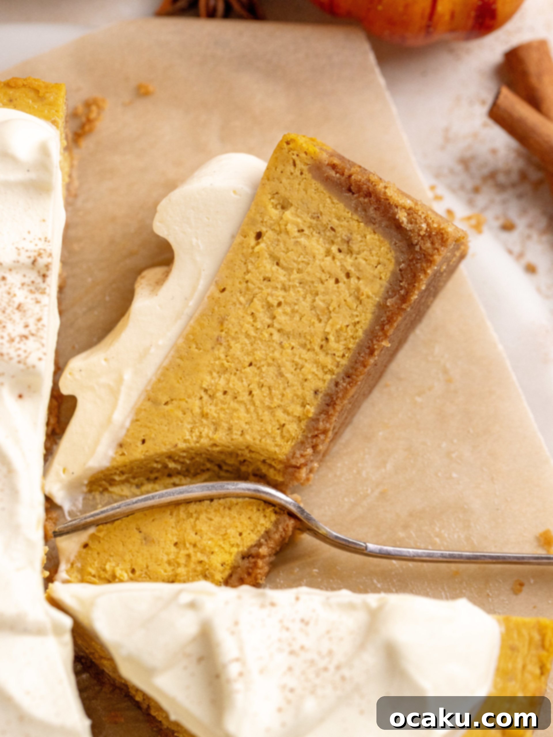 A perfectly sliced piece of pumpkin cheesecake resting on its side, showcasing its creamy texture and crust.