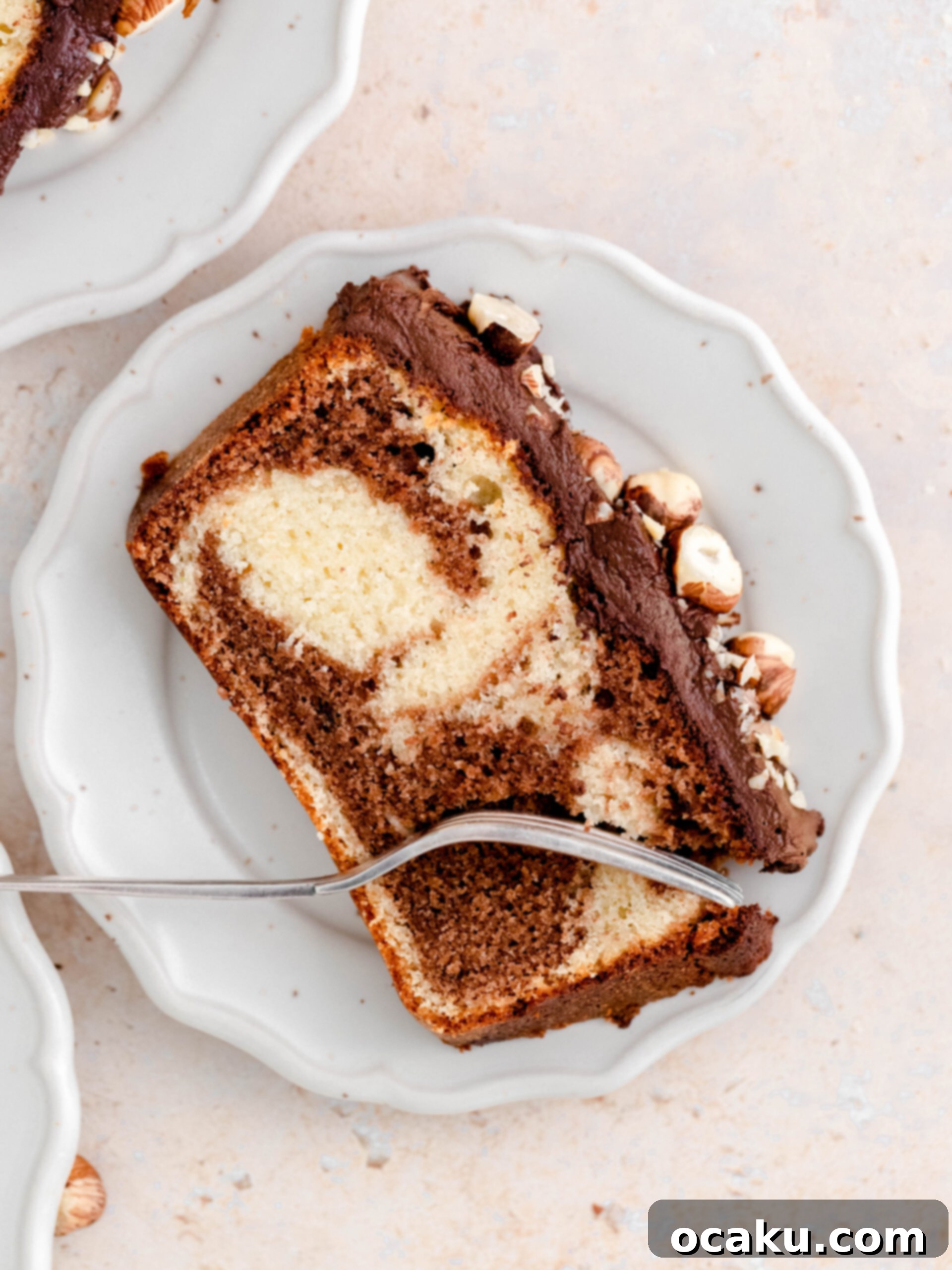 A perfectly sliced Nutella loaf cake showcasing the beautiful marbled vanilla and Nutella swirls, served on a white plate with a fork, ready to be savored.