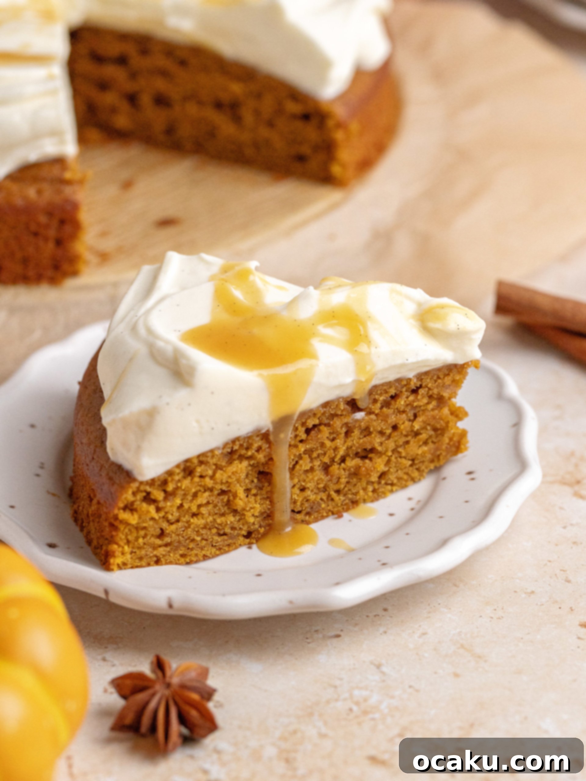 Maple Caramel Pumpkin Cake with Whipped Cream Cheese 2 A slice of brown butter pumpkin cake topped with a generous swirl of whipped cream cheese frosting and a drizzle of maple caramel on a white plate, ready to be enjoyed.