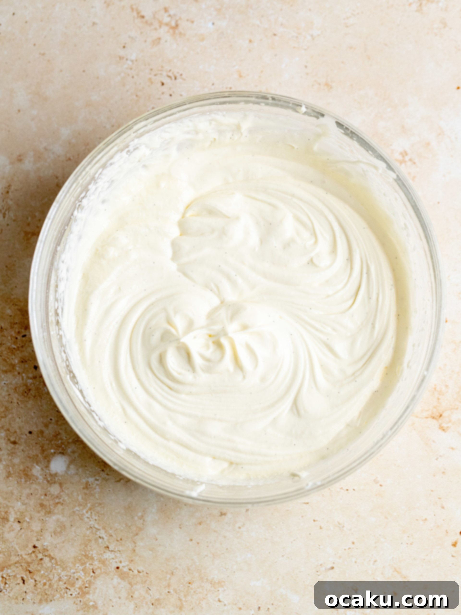 Maple Caramel Pumpkin Cake with Whipped Cream Cheese 6 Close-up of fluffy whipped cream cheese frosting being prepared in a mixing bowl with an electric mixer.