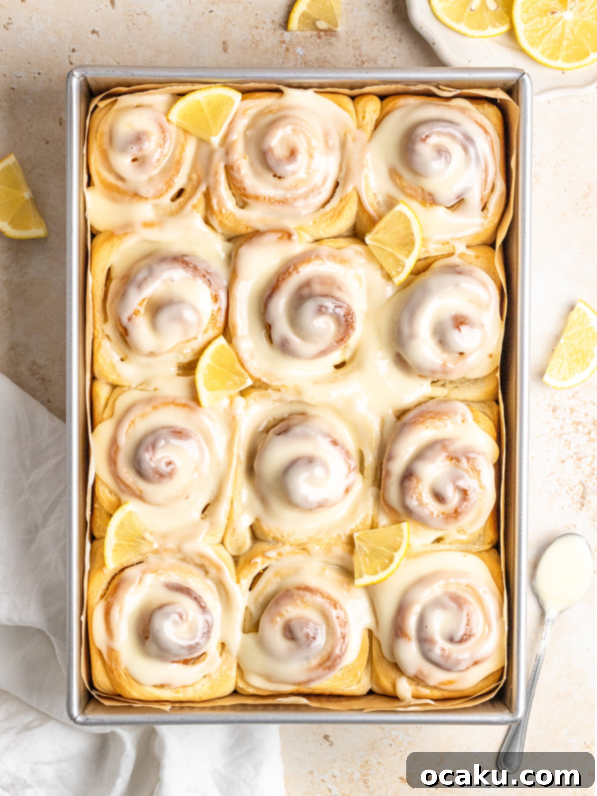 Baked lemon rolls with cream cheese frosting in a baking dish.