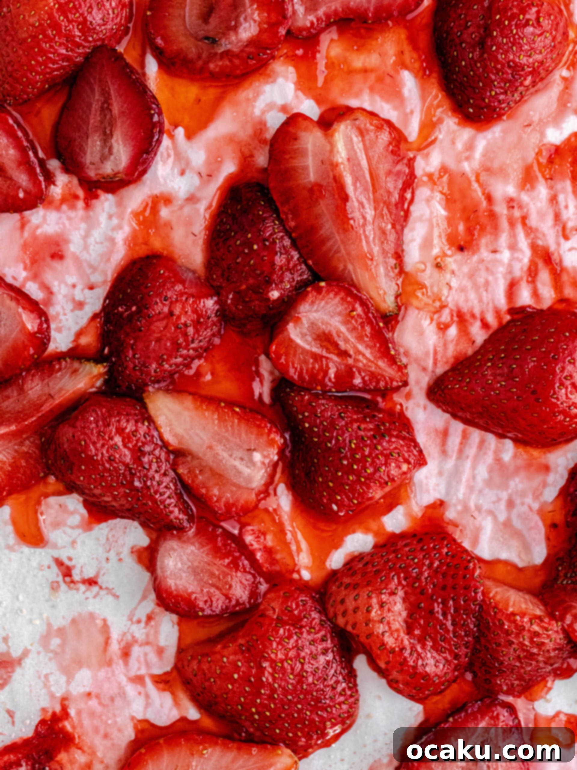 Baked strawberries on a tray. Rich red strawberries, some with a slight caramelized sheen, sit on a baking sheet lined with parchment paper.