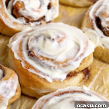 A giant cinnamon roll with generous cream cheese frosting, ready to eat.