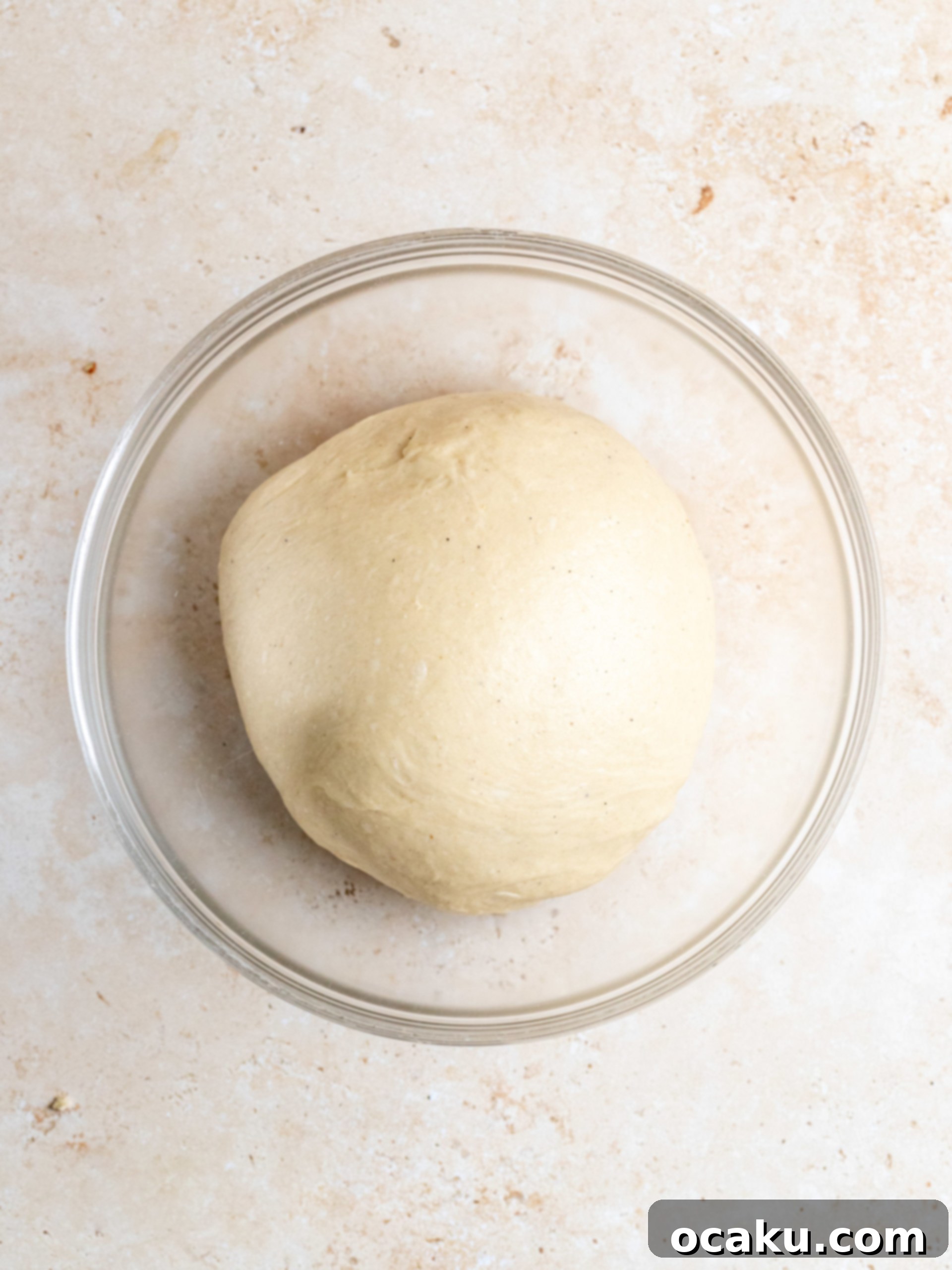 Dough in a stand mixer with a dough hook, starting to come together.