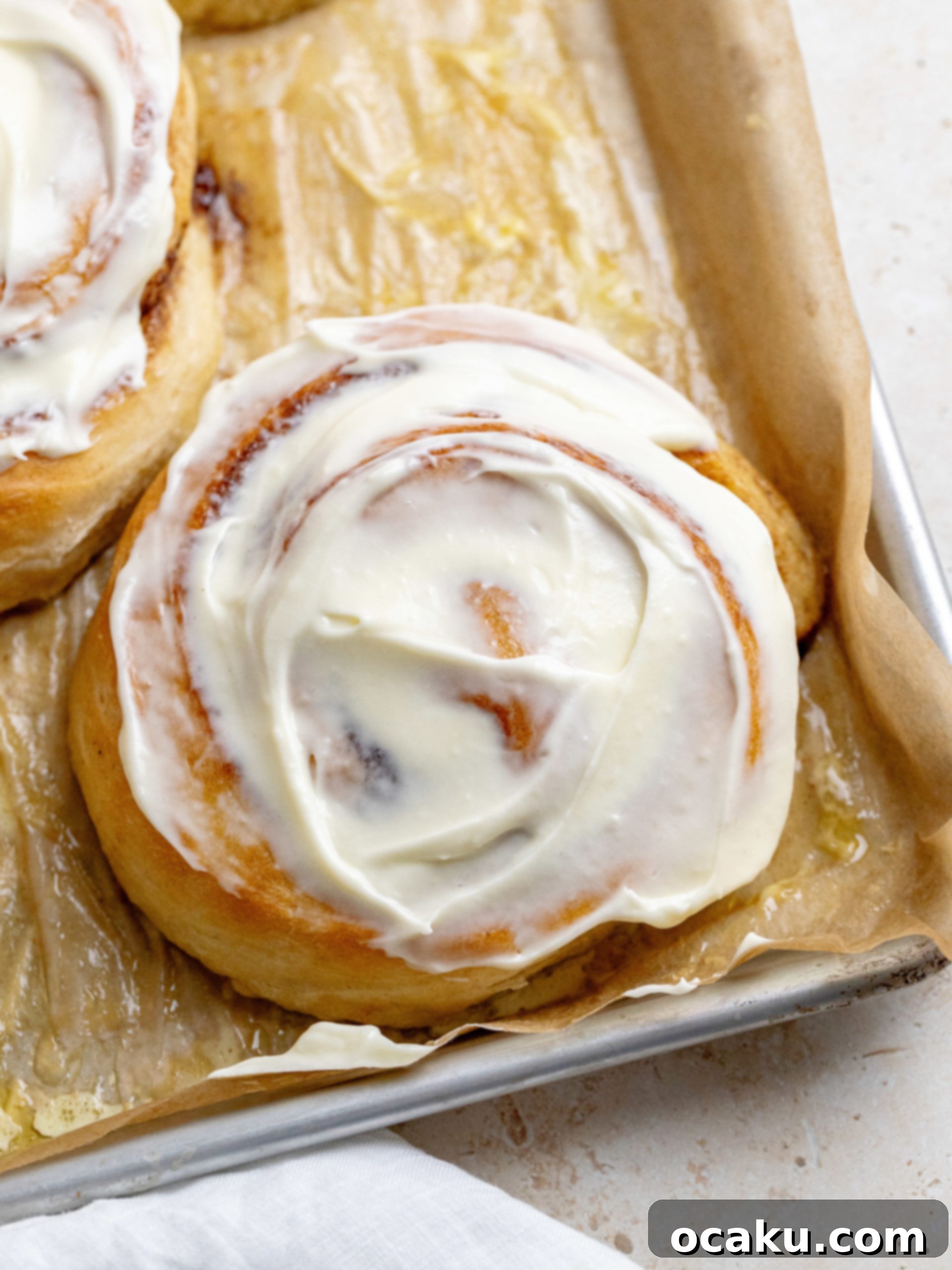 Multiple giant cinnamon rolls on a baking sheet, freshly baked and still warm.