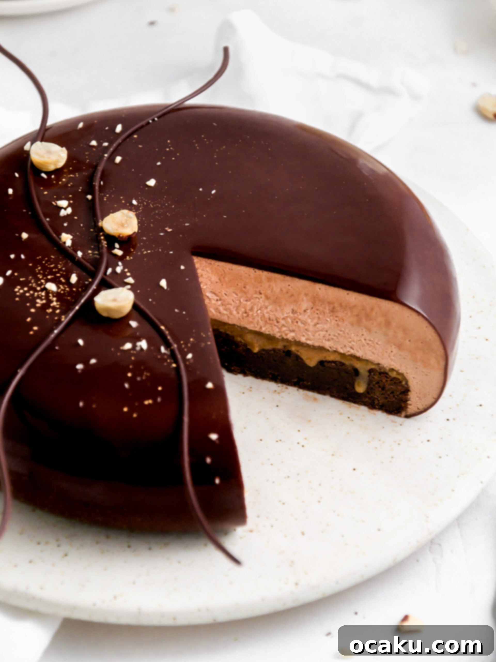 Decadent Nutella Brownie Mousse Cake 2 A perfectly cut slice revealing the distinct layers of the fudgy brownie, hazelnut praline, and creamy Nutella mousse in the Nutella mousse cake.