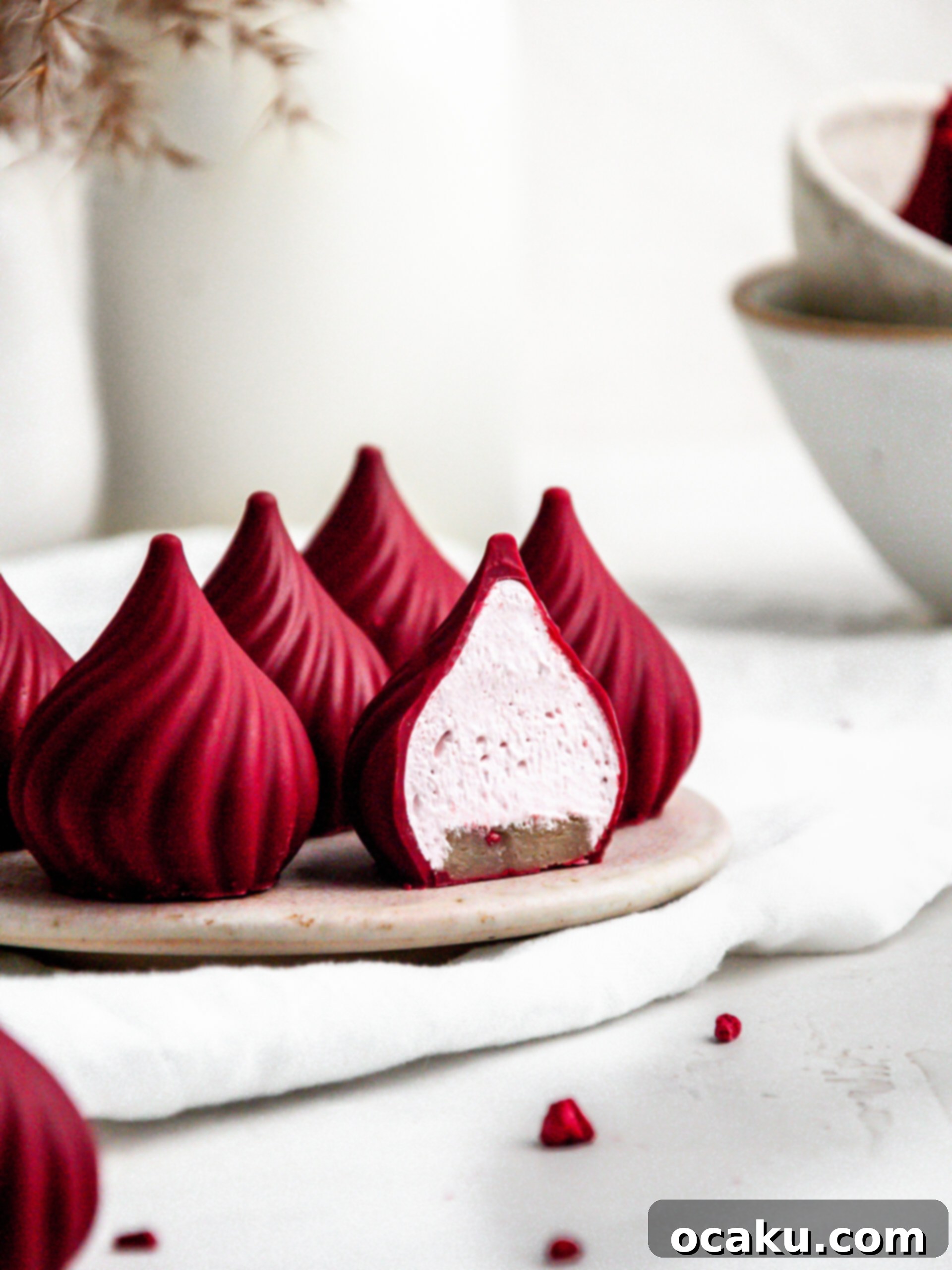 A raspberry cream puff halved to show the layers of chocolate, marshmallow fluff, and marzipan base.