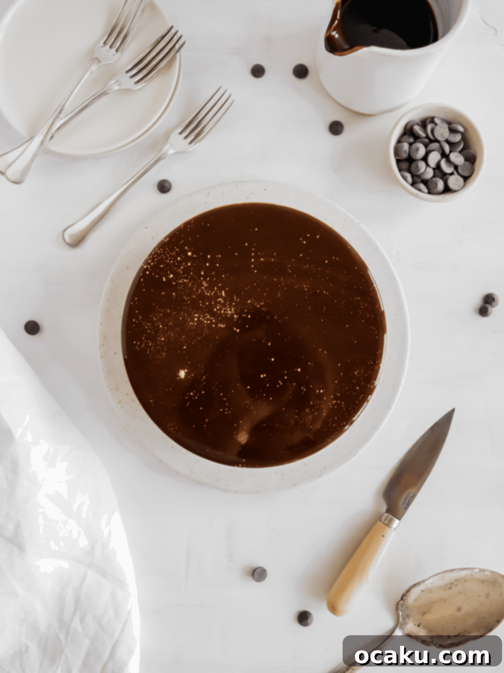 A stunningly decorated chocolate and caramel mousse cake, gleaming with its mirror glaze, presented on a cake tray.