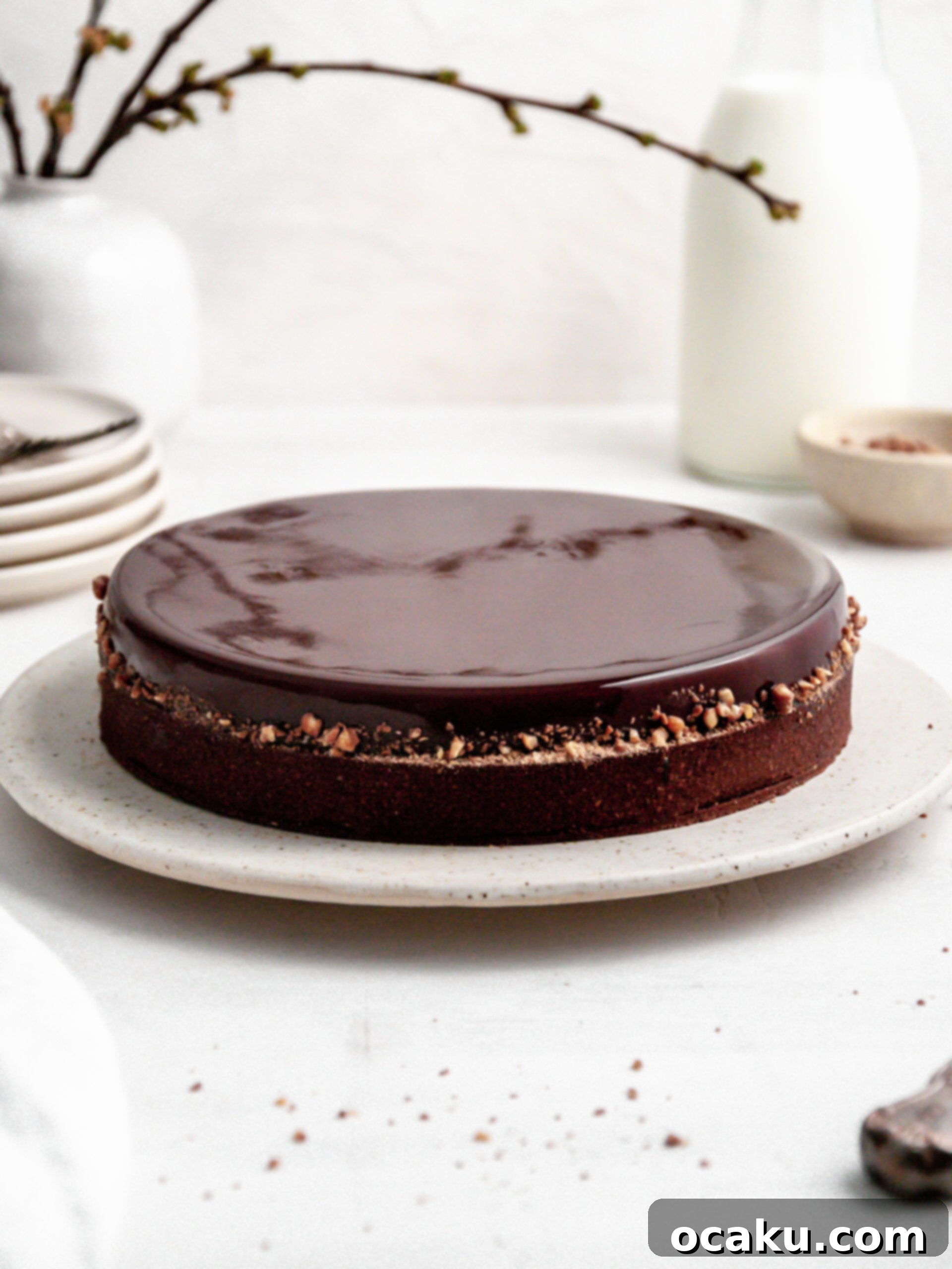 A beautifully presented Chocolate Coffee and Caramel Tart on an elegant cake stand, showcasing its glossy glaze and rich layers.