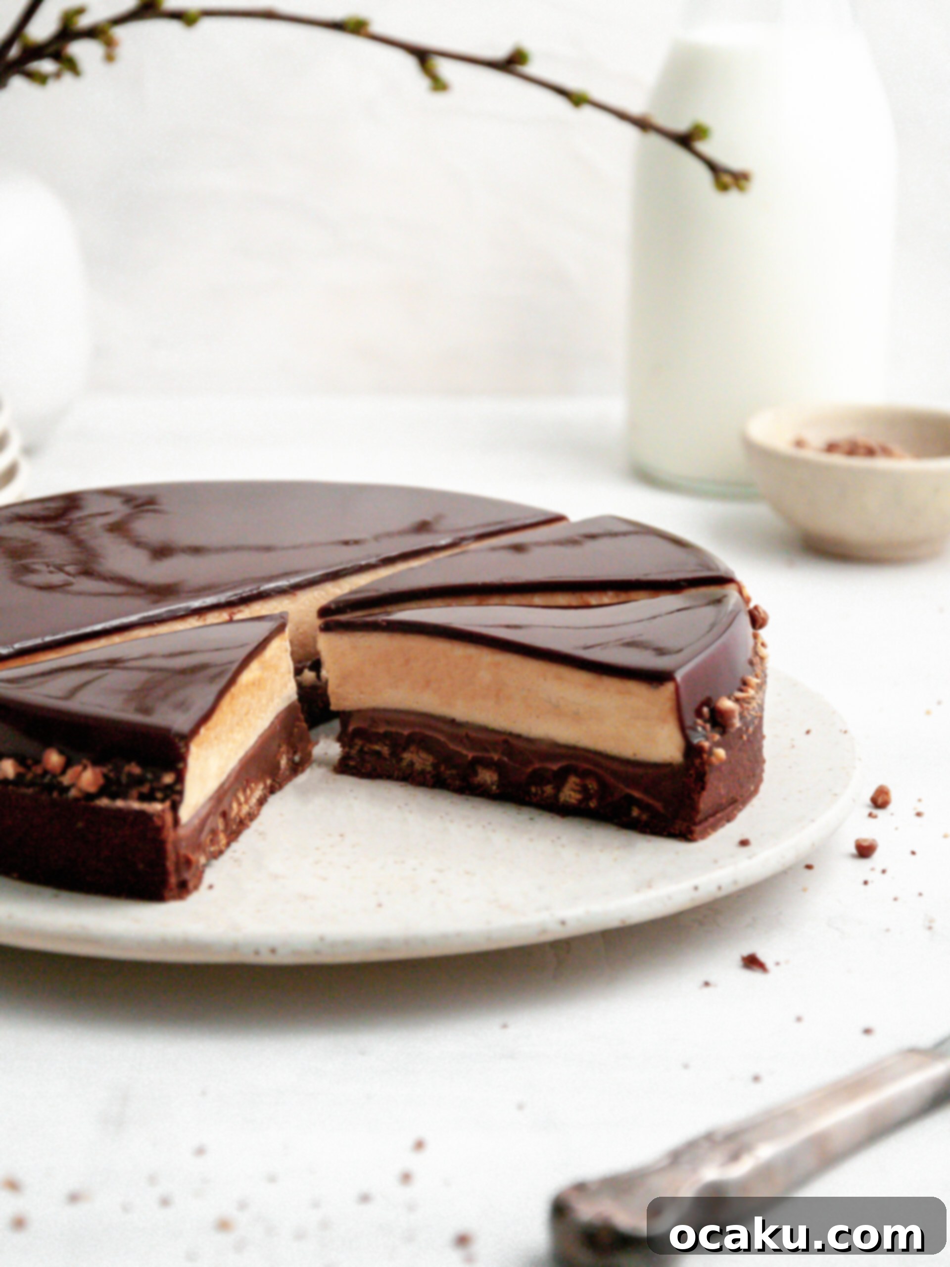 A slice of the Chocolate Coffee and Caramel Tart, revealing its distinct layers of cacao crust, chocolate crunch, coffee ganache, and caramel mousse.