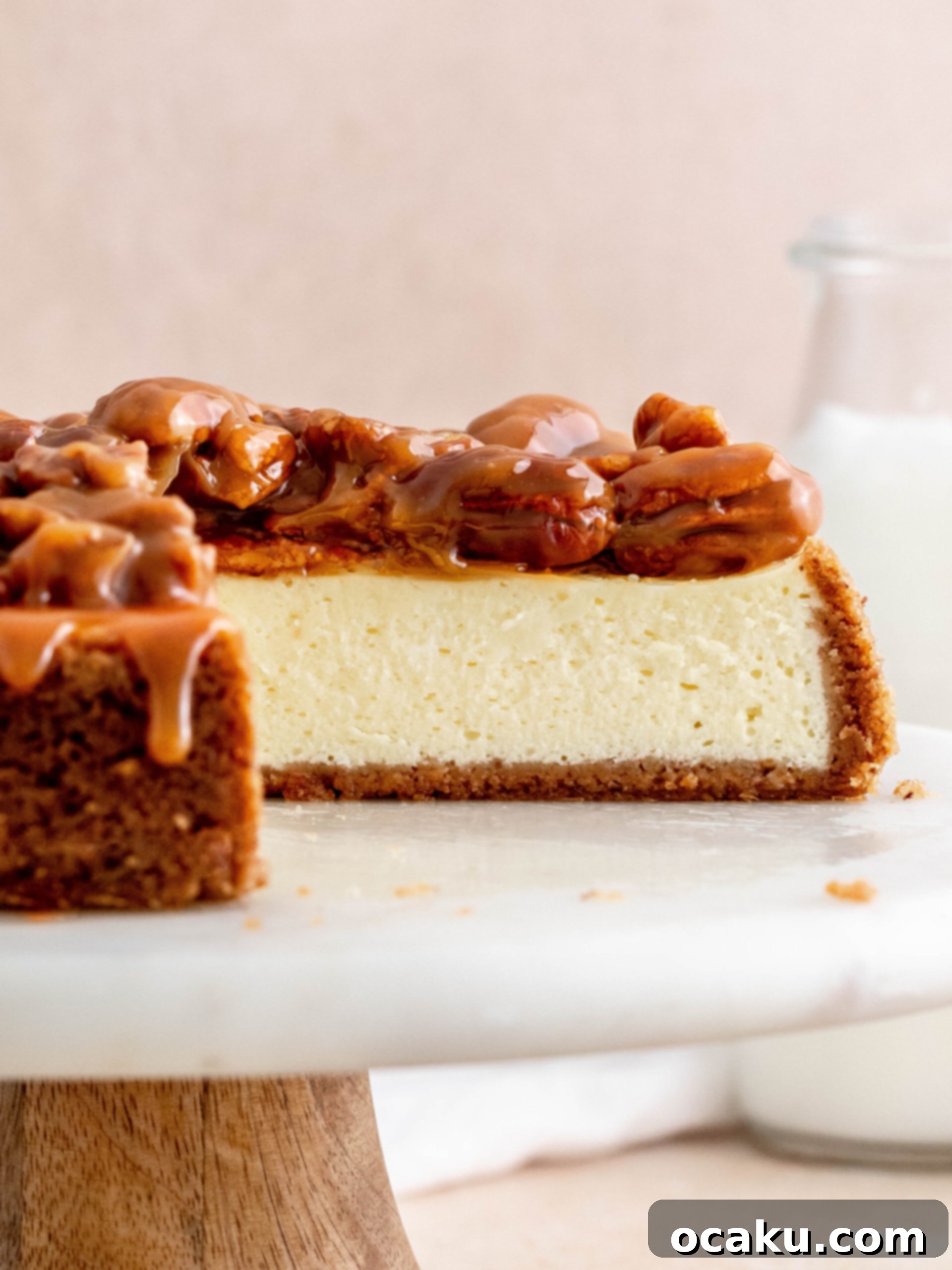 A whole Caramel Pecan Cheesecake on an elegant cake stand, ready to be served.