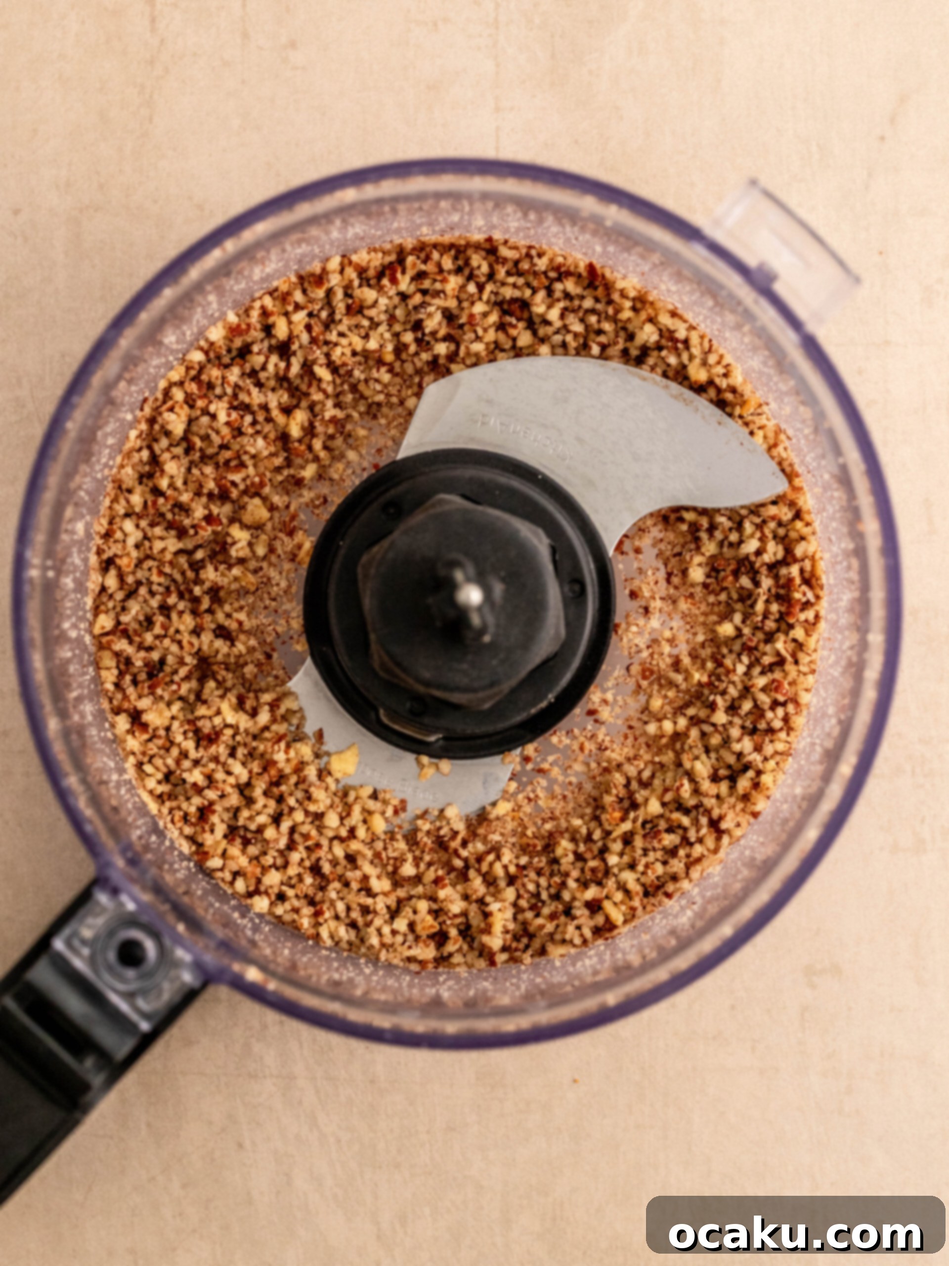 Step-by-step image showing finely chopped pecan nuts in a food processor, ready for the crust.