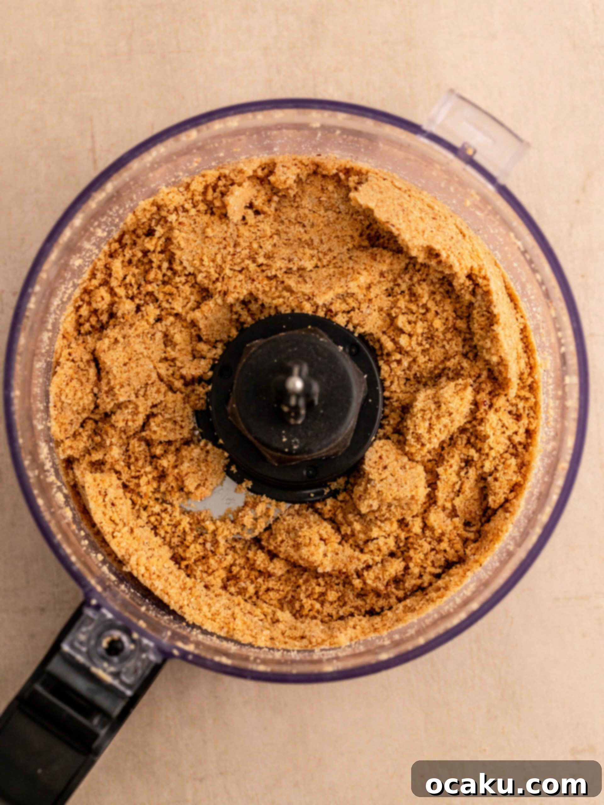 Step-by-step image showing digestive cookies being blended with pecan nuts and sugar for the cheesecake crust.