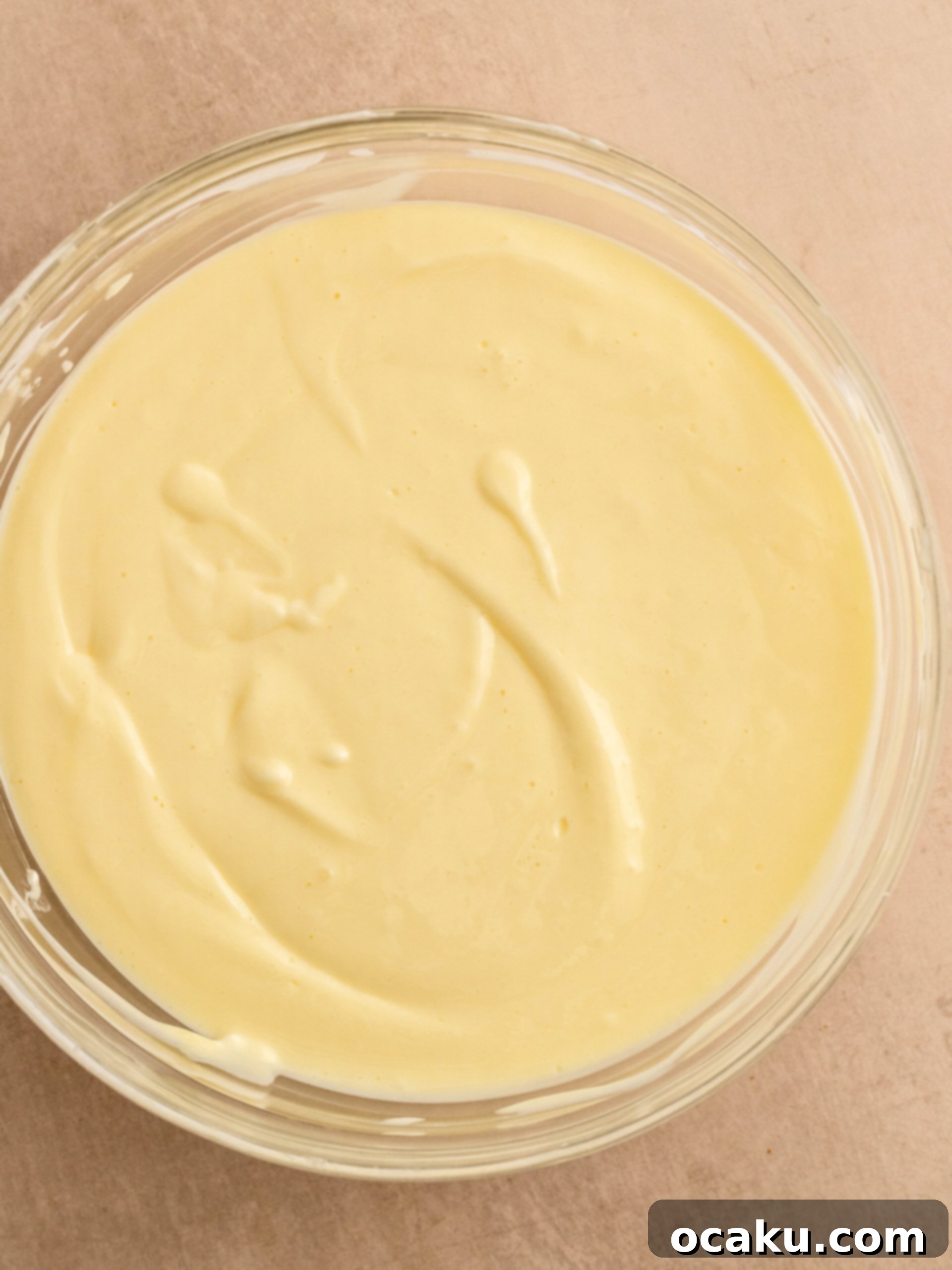 Step-by-step image showing cheesecake batter being mixed in a stand mixer.