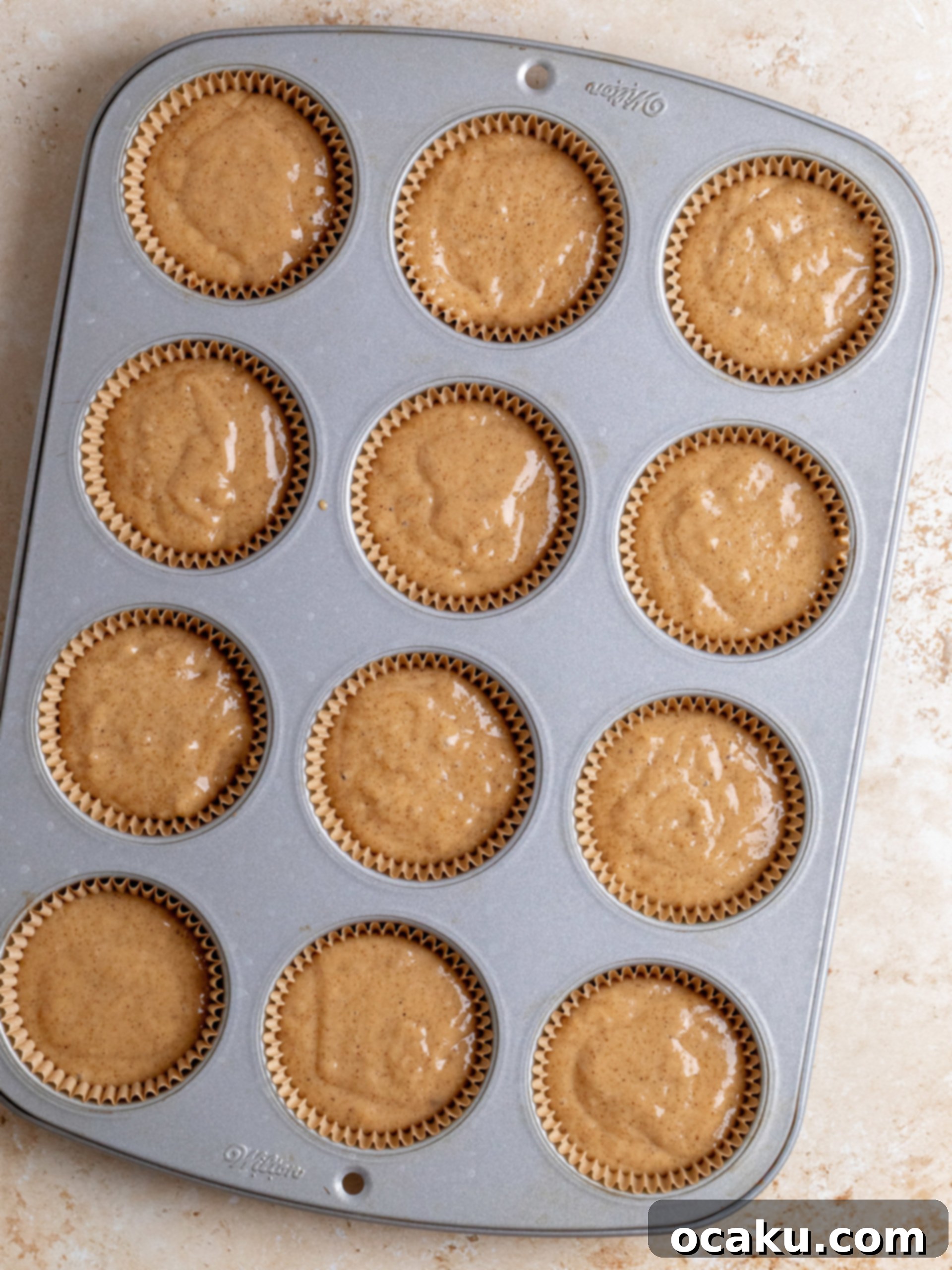 Decadent Cinnamon Cupcakes 6 Cupcake liners in a baking pan, filled with batter and ready for the oven.