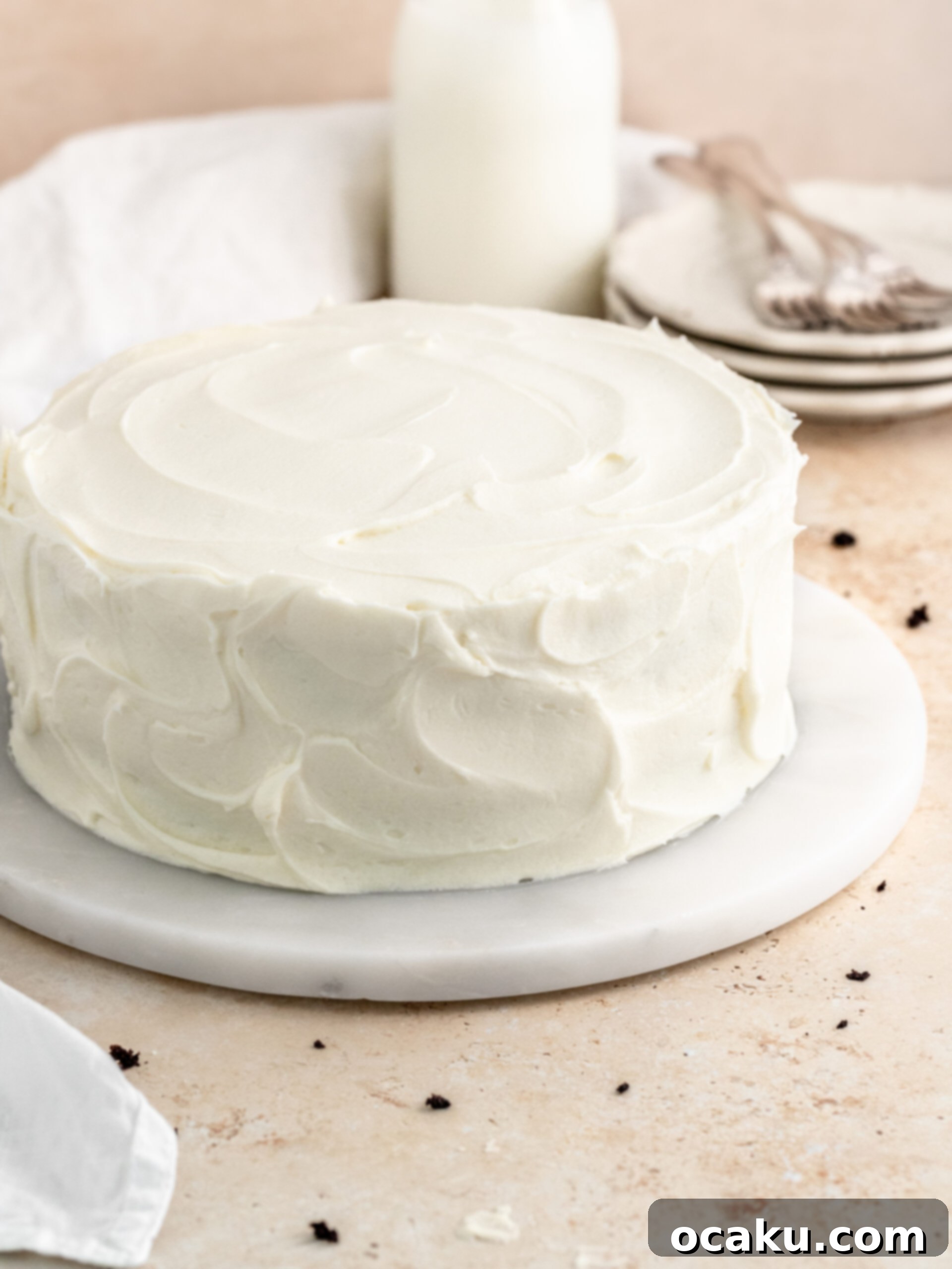 A beautifully assembled chocolate cake with cream cheese frosting, awaiting its final touches.