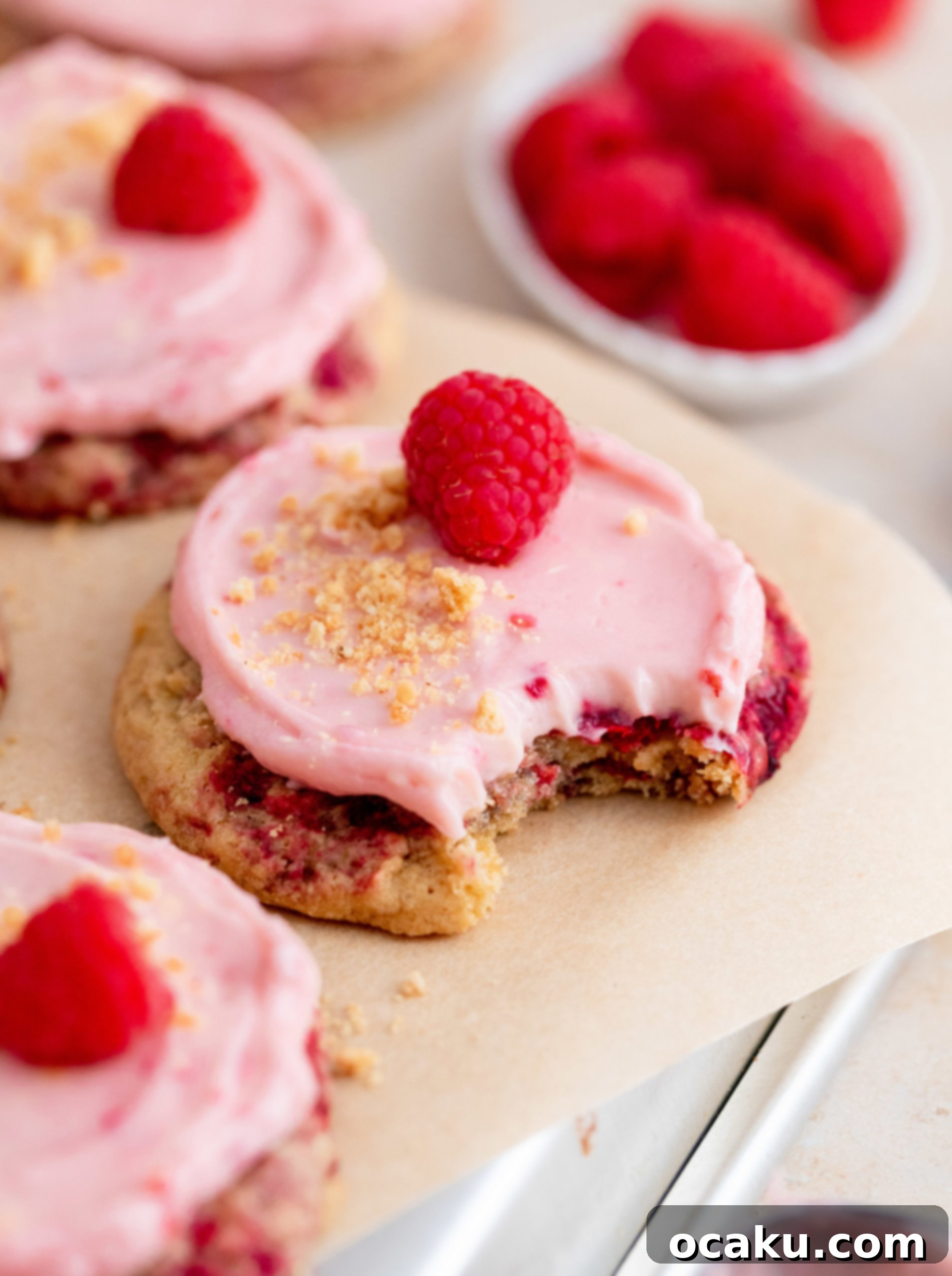 A stack of raspberry cheesecake cookies with fresh raspberries and graham cracker crumbs.