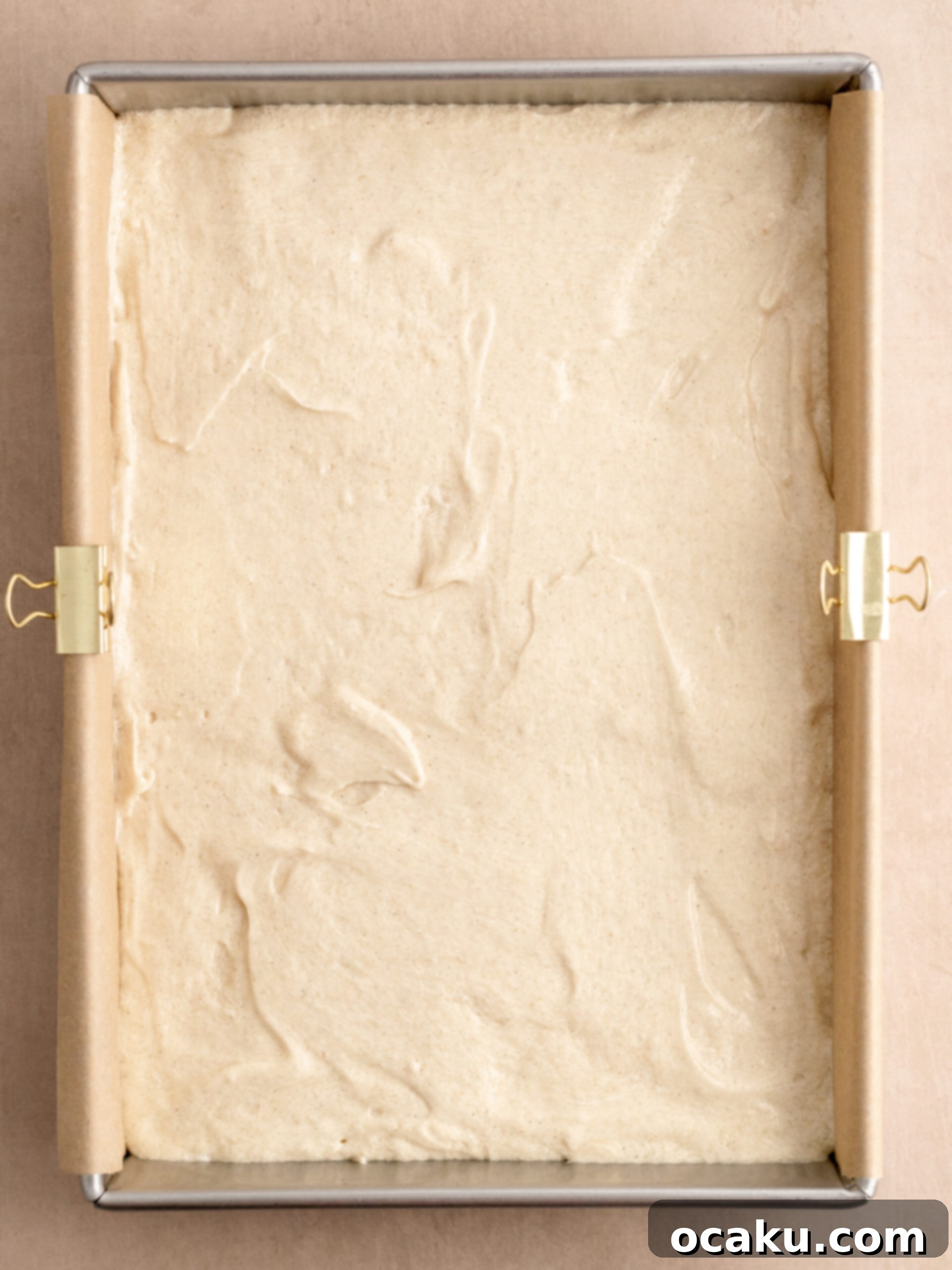 Step 2: Cake batter spread evenly in a parchment-lined sheet pan, ready for baking.