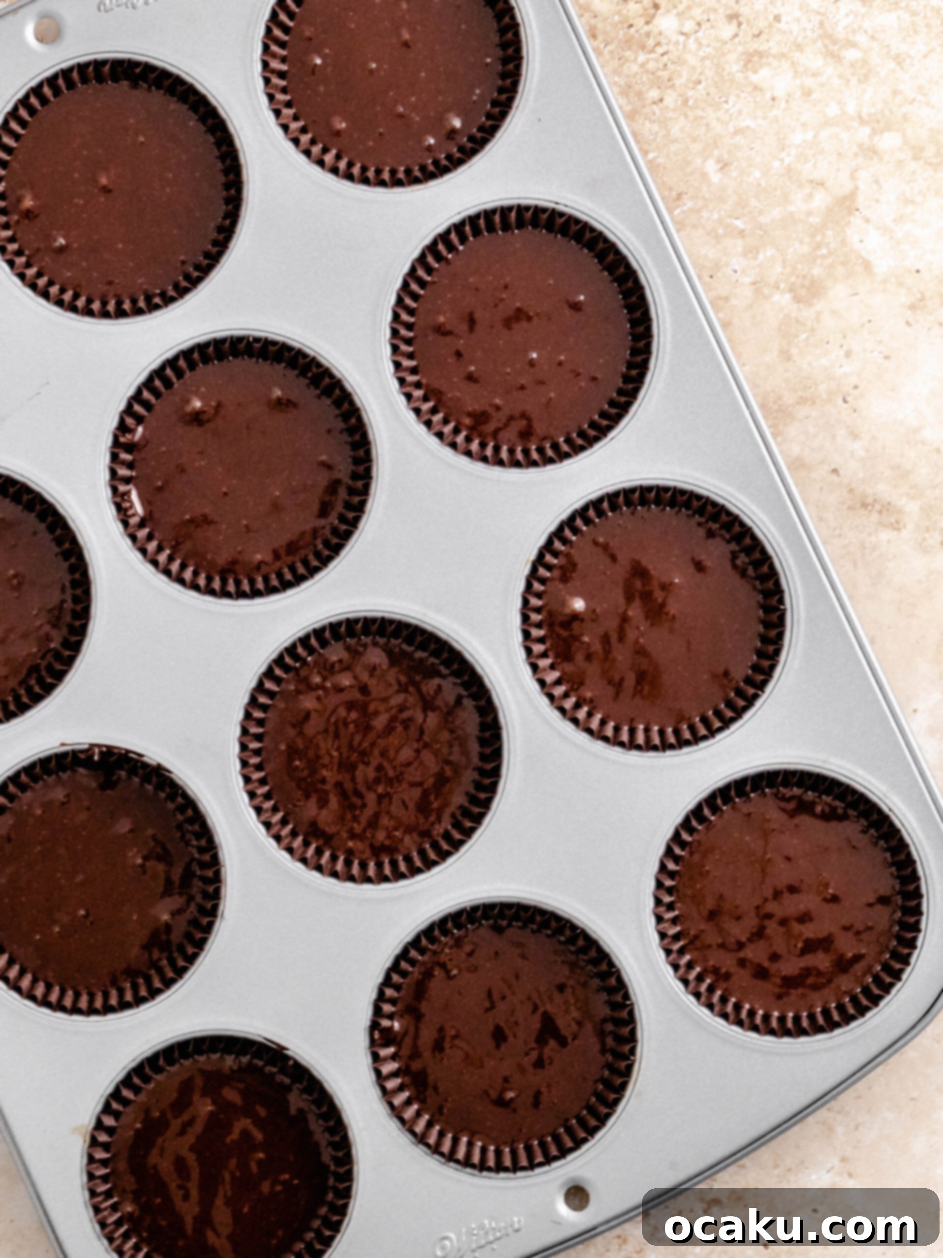 Cupcake batter divided into liners in a baking tray.