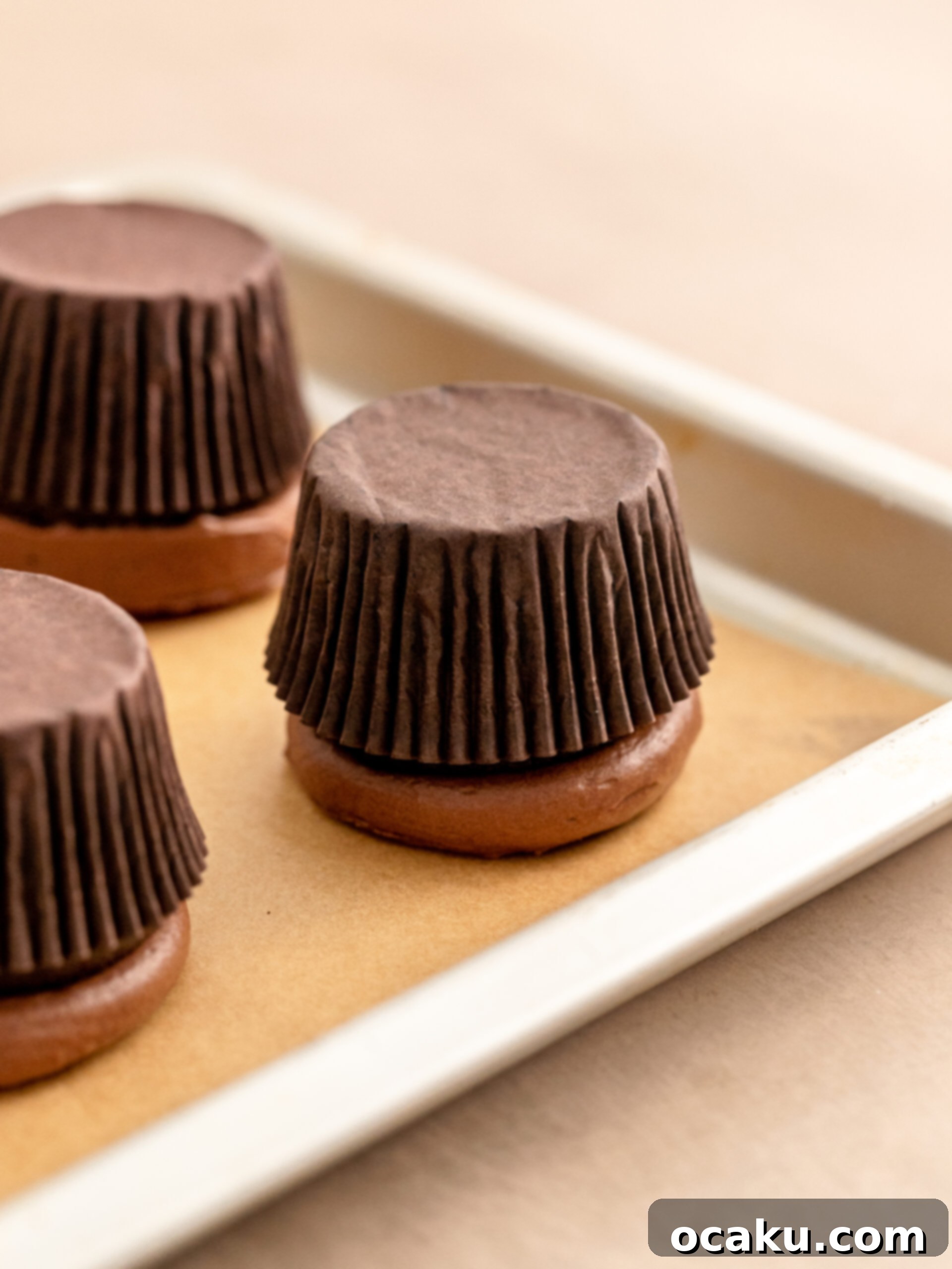 Cupcakes inverted onto parchment paper to flatten frosting.