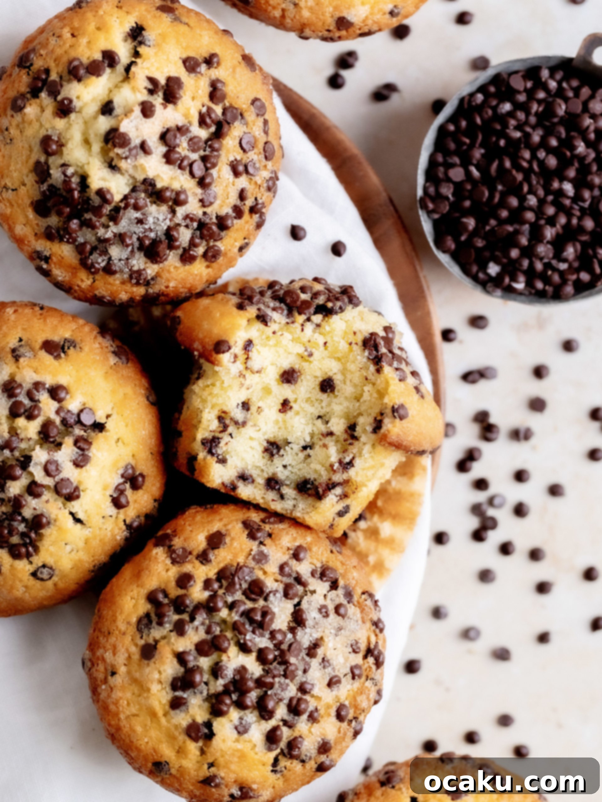 A stack of three bakery-style chocolate chip muffins on a cooling rack, ready to be eaten.