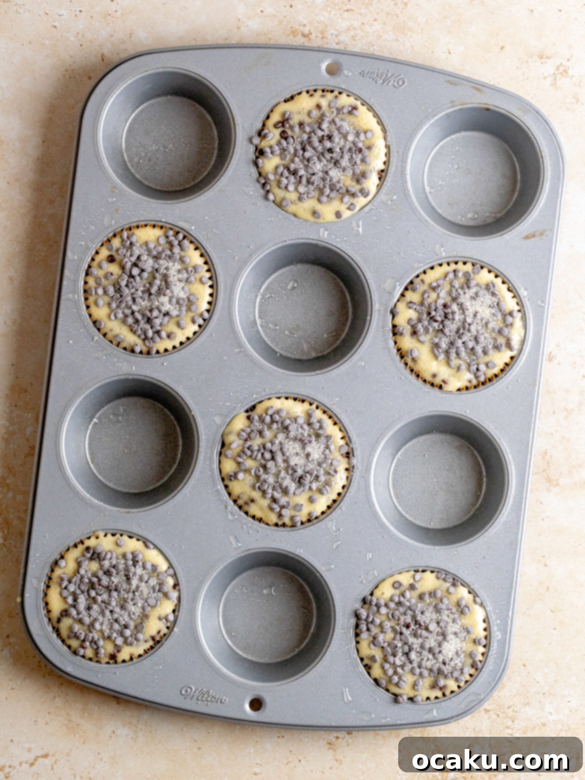 Image showing muffins topped with extra chocolate chips and cane sugar before baking.