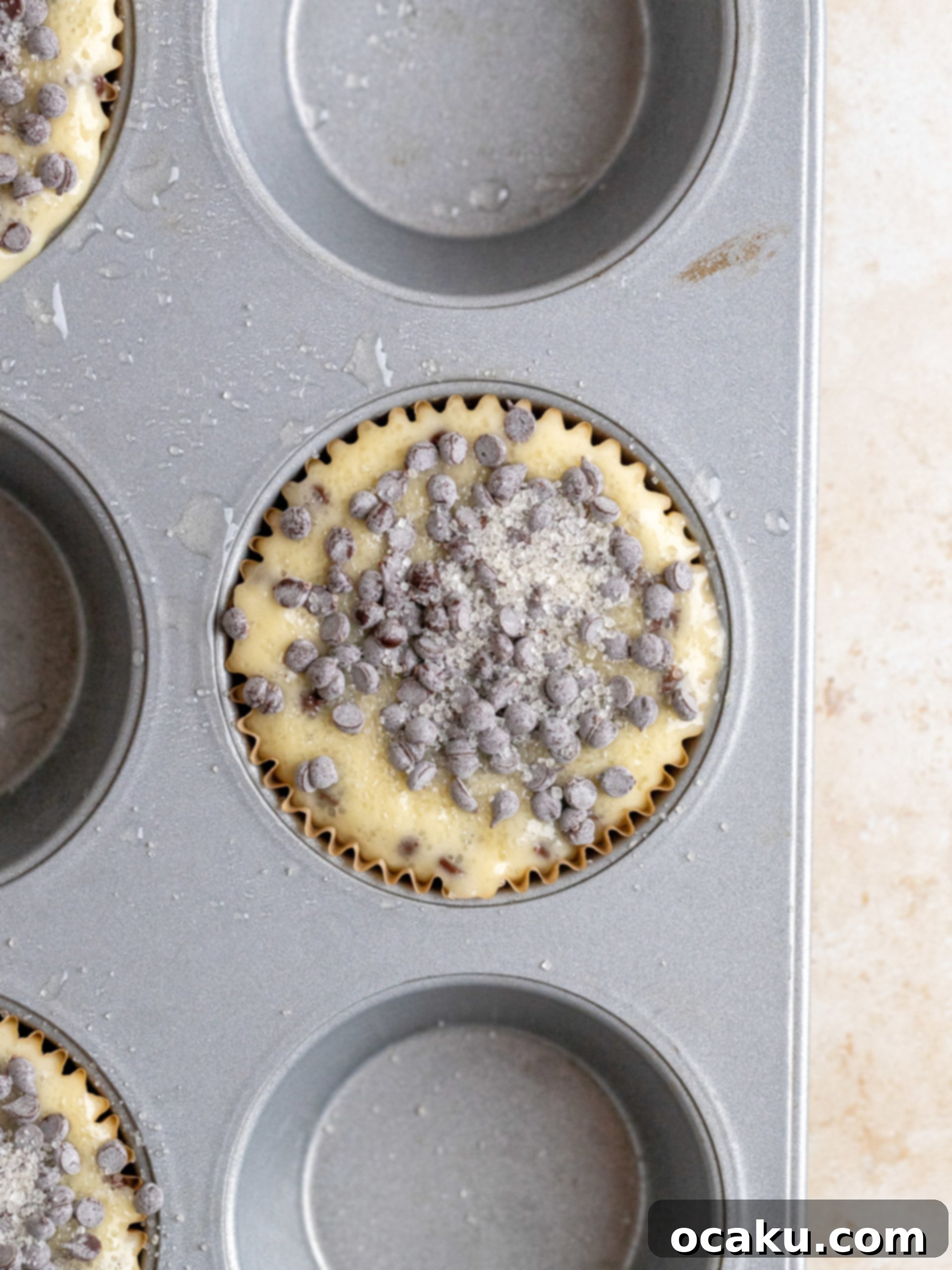 Baked chocolate chip muffins with tall domes, cooling in the pan.