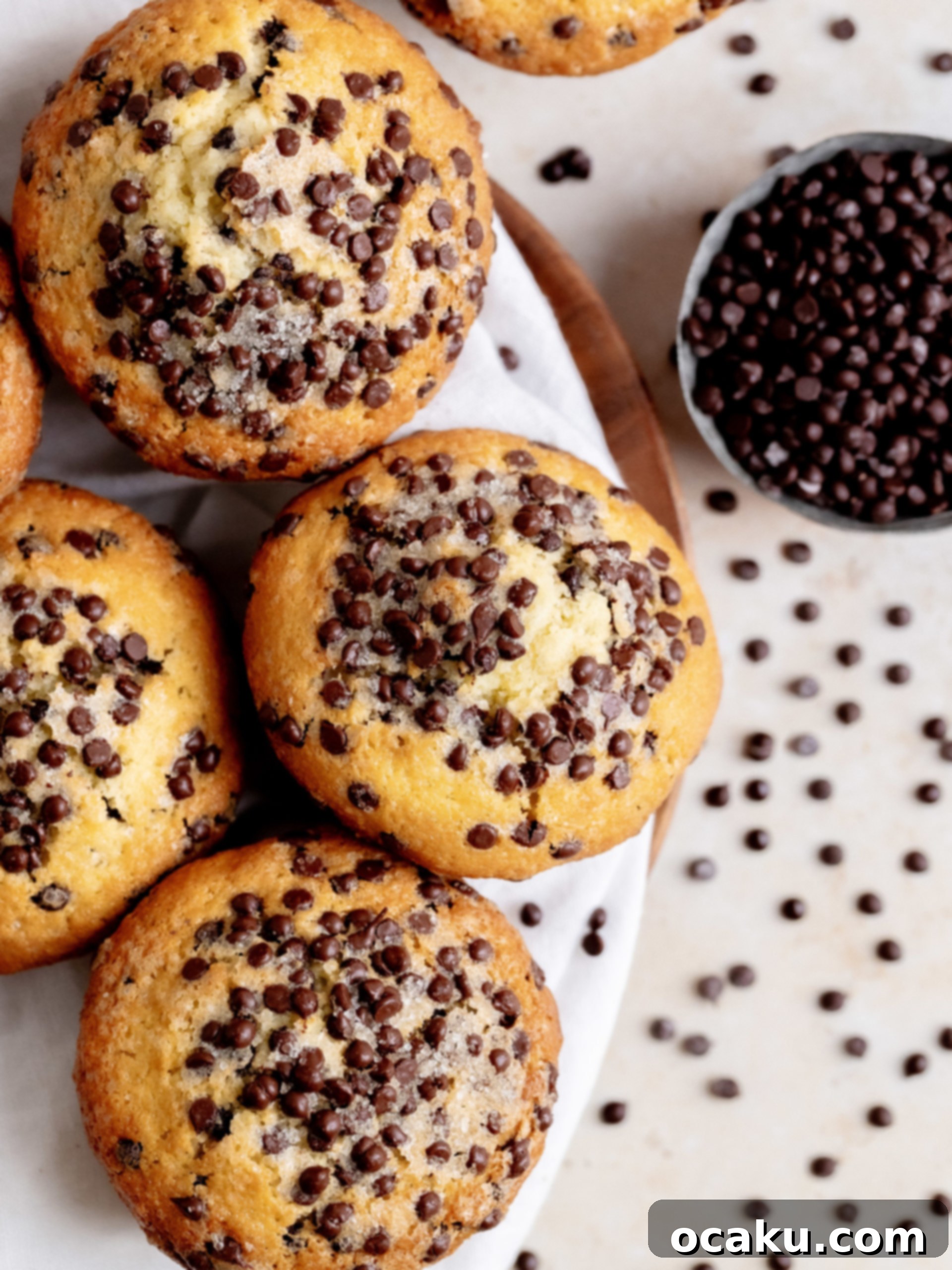 A perfectly baked chocolate chip muffin, split open to show its moist, fluffy interior and melted chocolate.