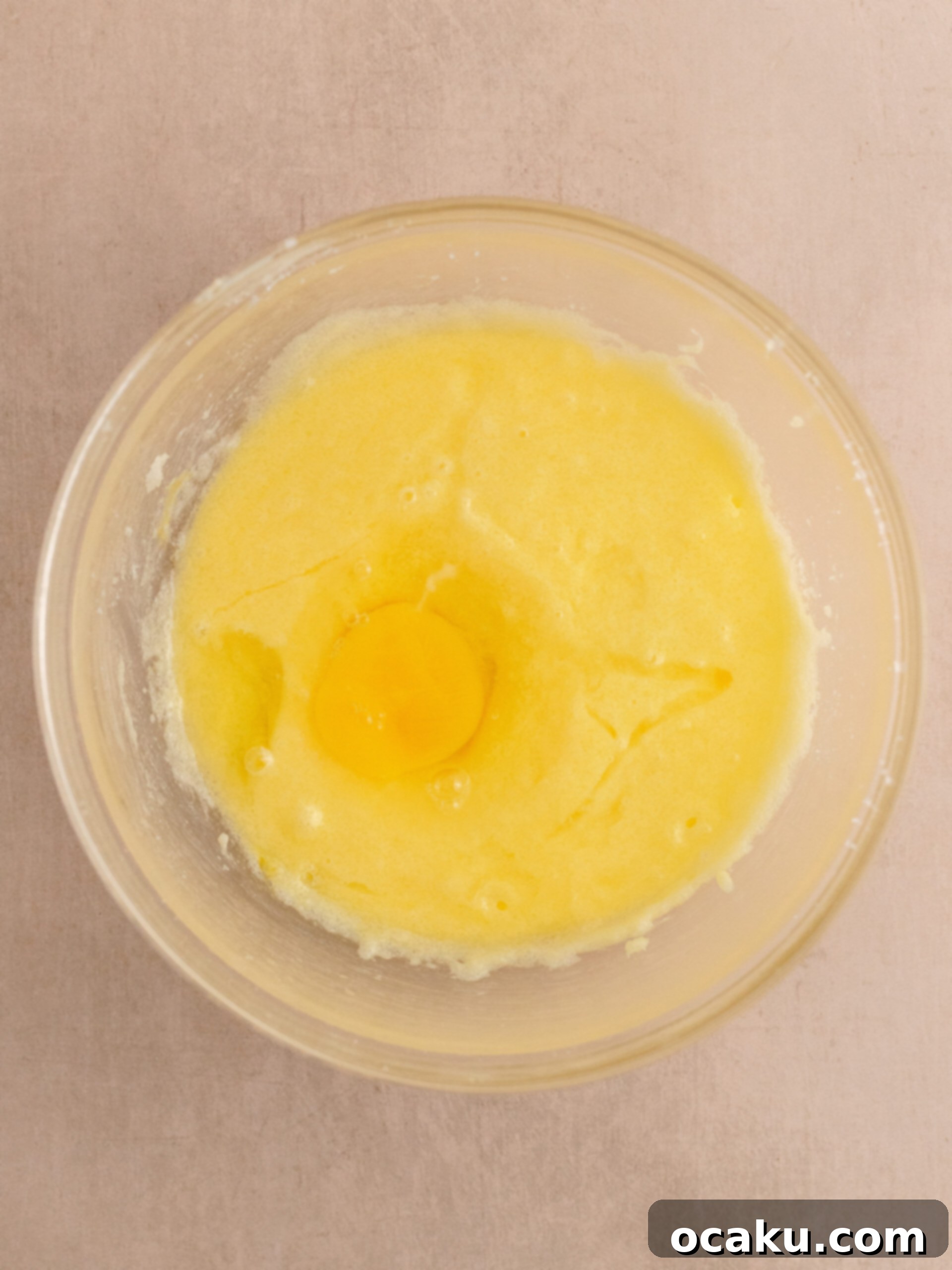 Eggs being added one by one to the creamed butter and sugar mixture.