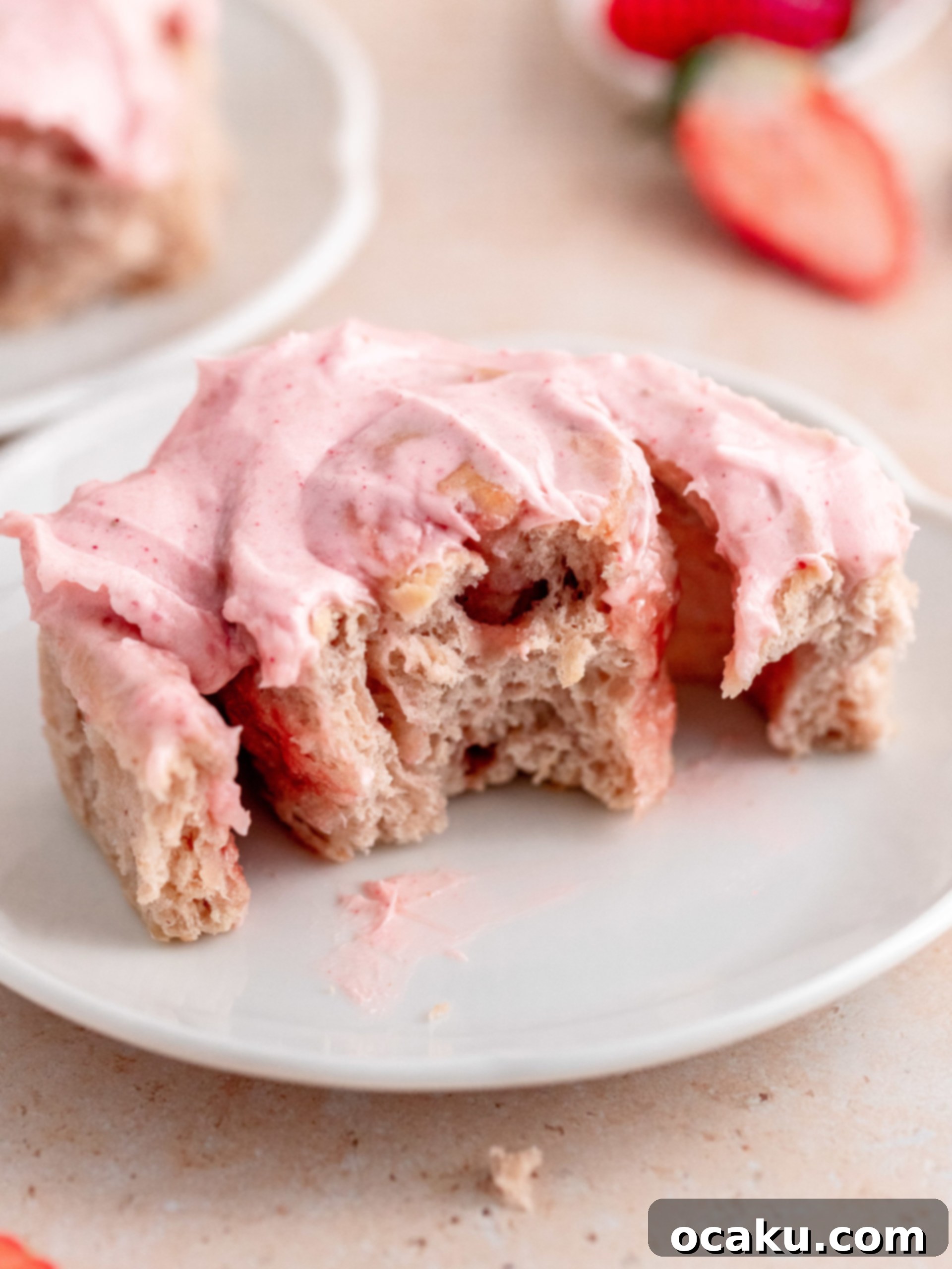 A stack of perfectly baked and frosted strawberry rolls on a wire rack, with some artfully placed fresh strawberries.