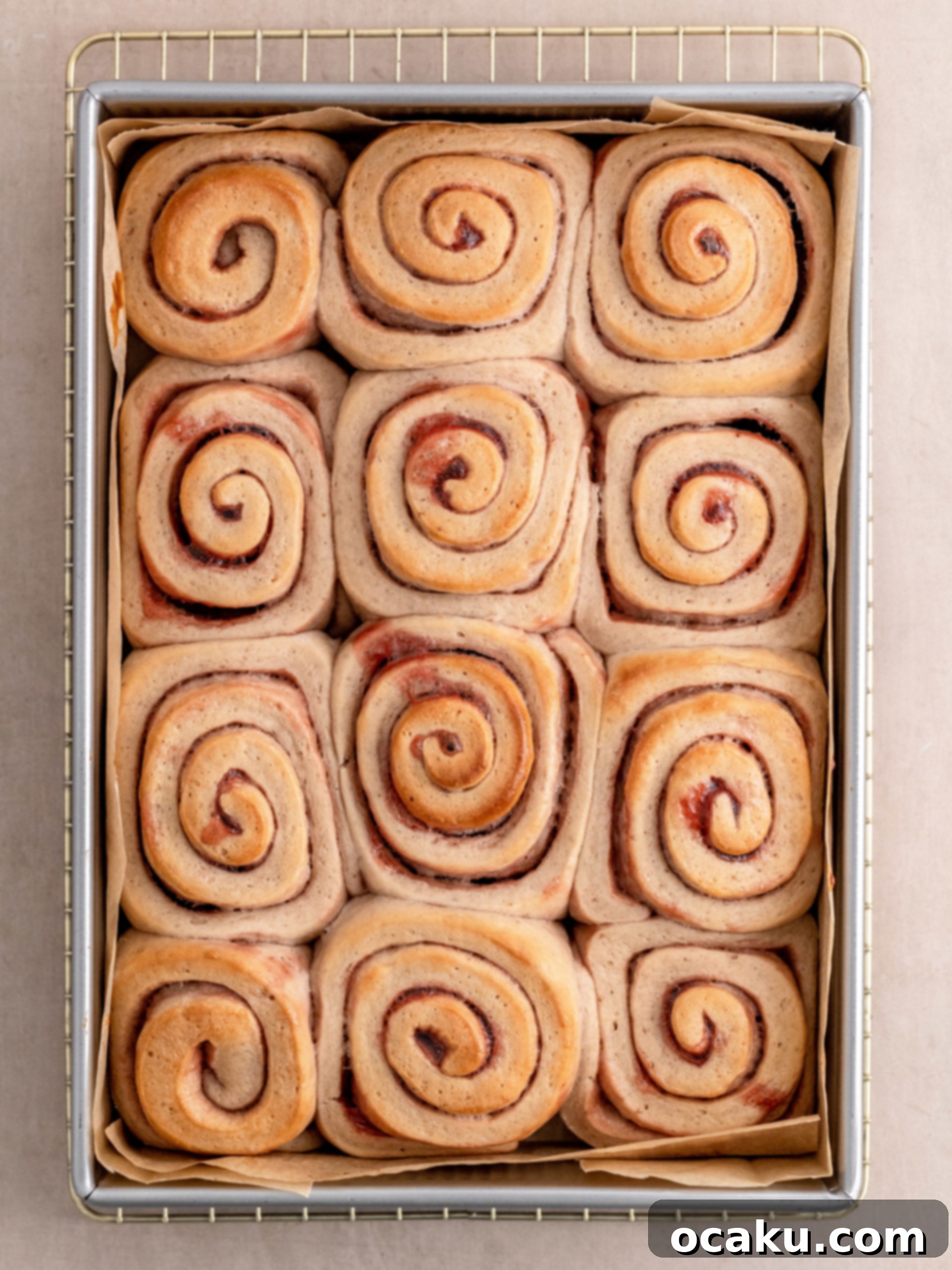 Delicious strawberry rolls, generously topped with pink cream cheese frosting, some with sprinkles, served on a plate.