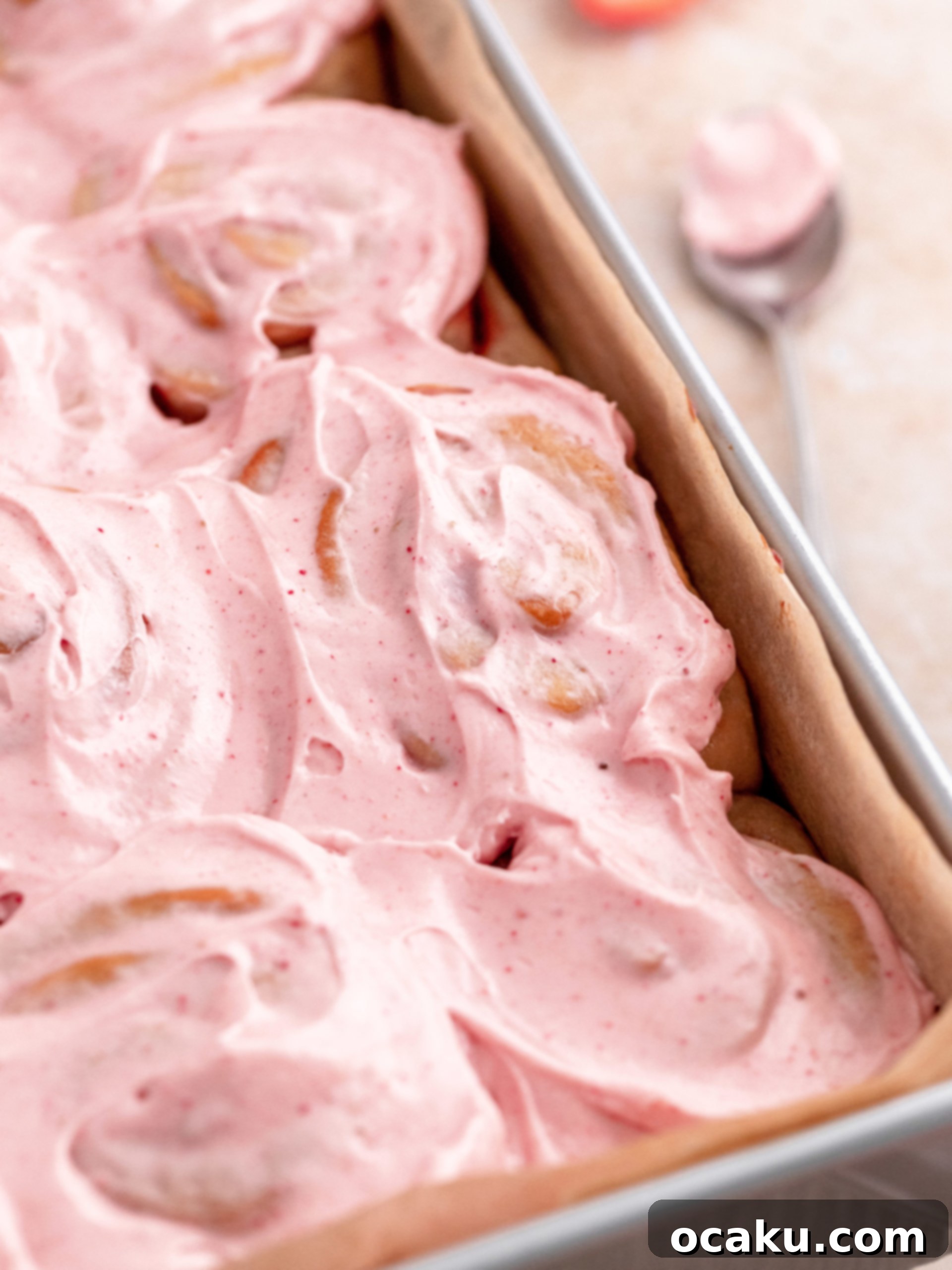 A close-up shot of a single perfectly frosted strawberry roll on a plate, showing its soft texture and berry filling.