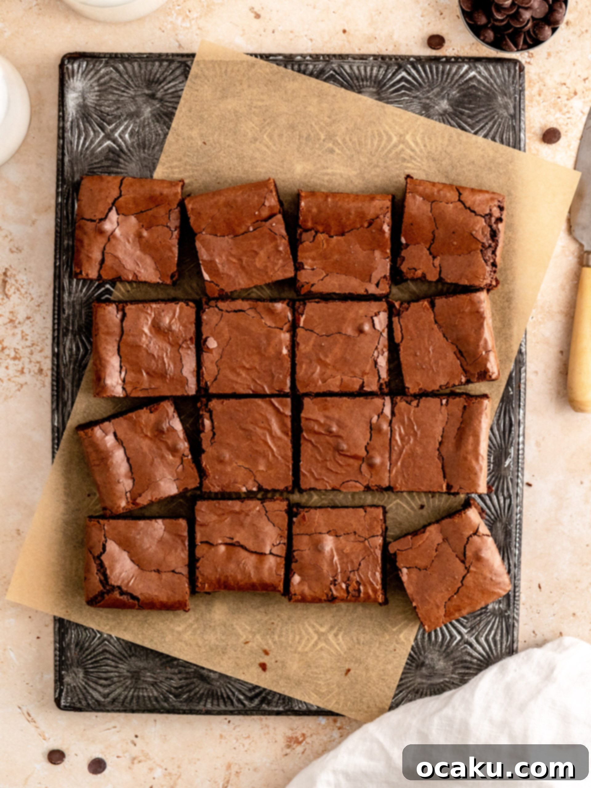 Two hands reaching for a pan of freshly baked, warm, and fudgy dairy-free brownies.