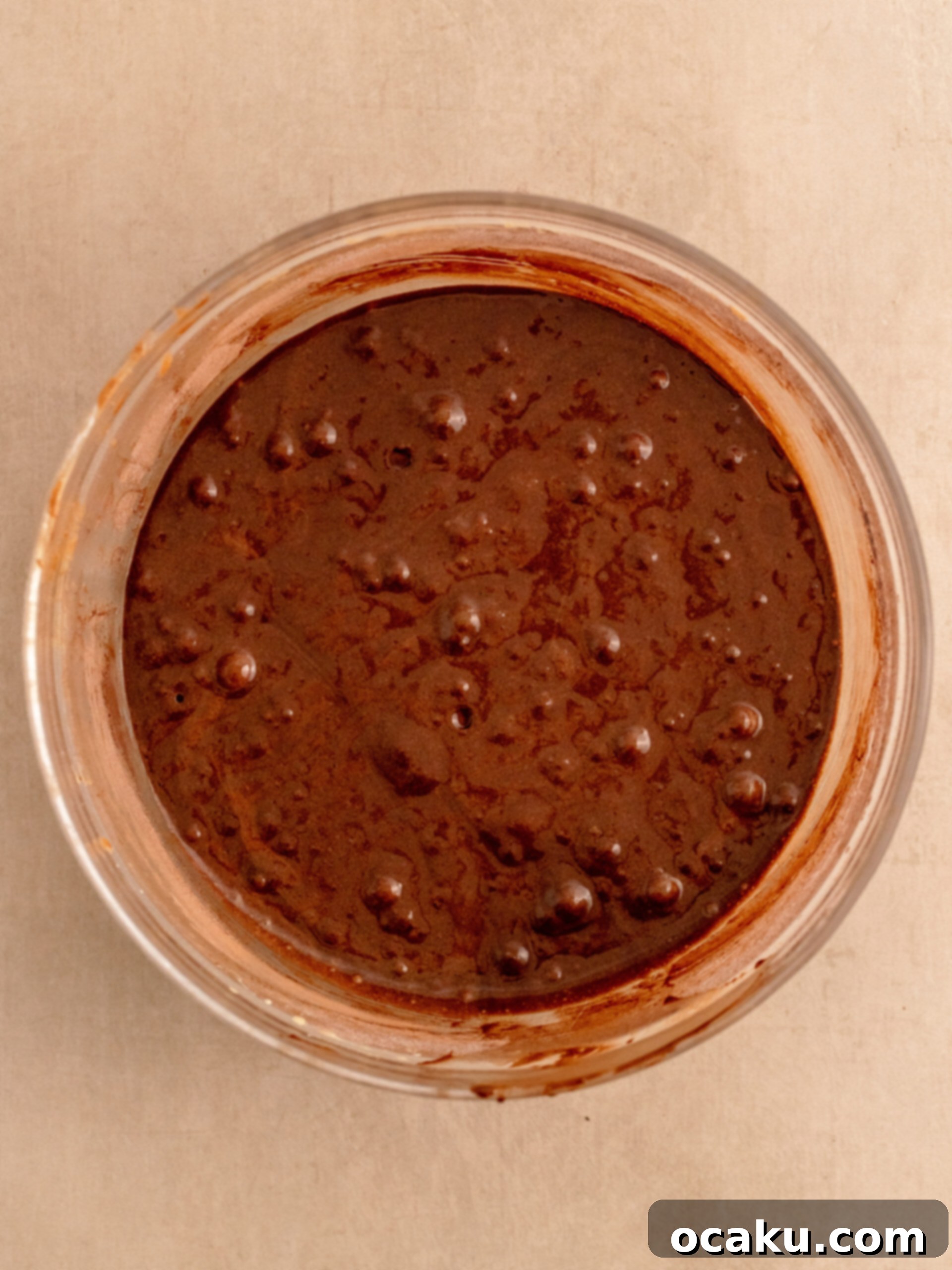 Scraping down the sides of the mixing bowl with a spatula to ensure all ingredients are well incorporated.