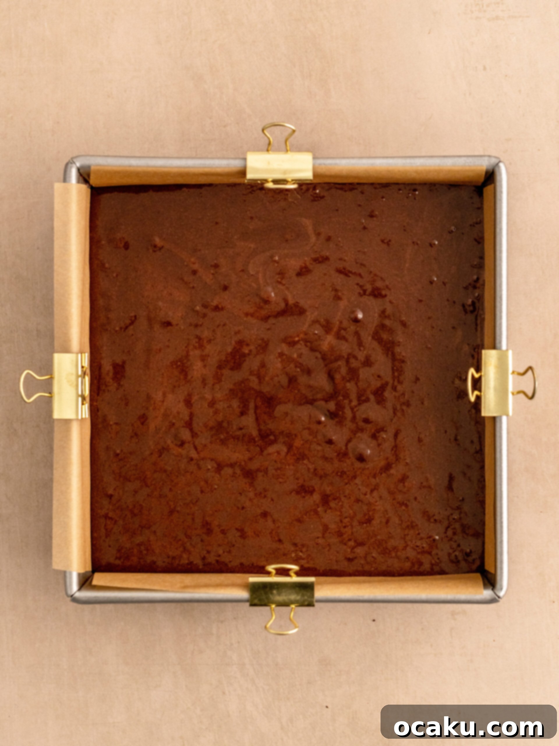 Pouring the rich dairy-free brownie batter into a parchment-lined baking pan.