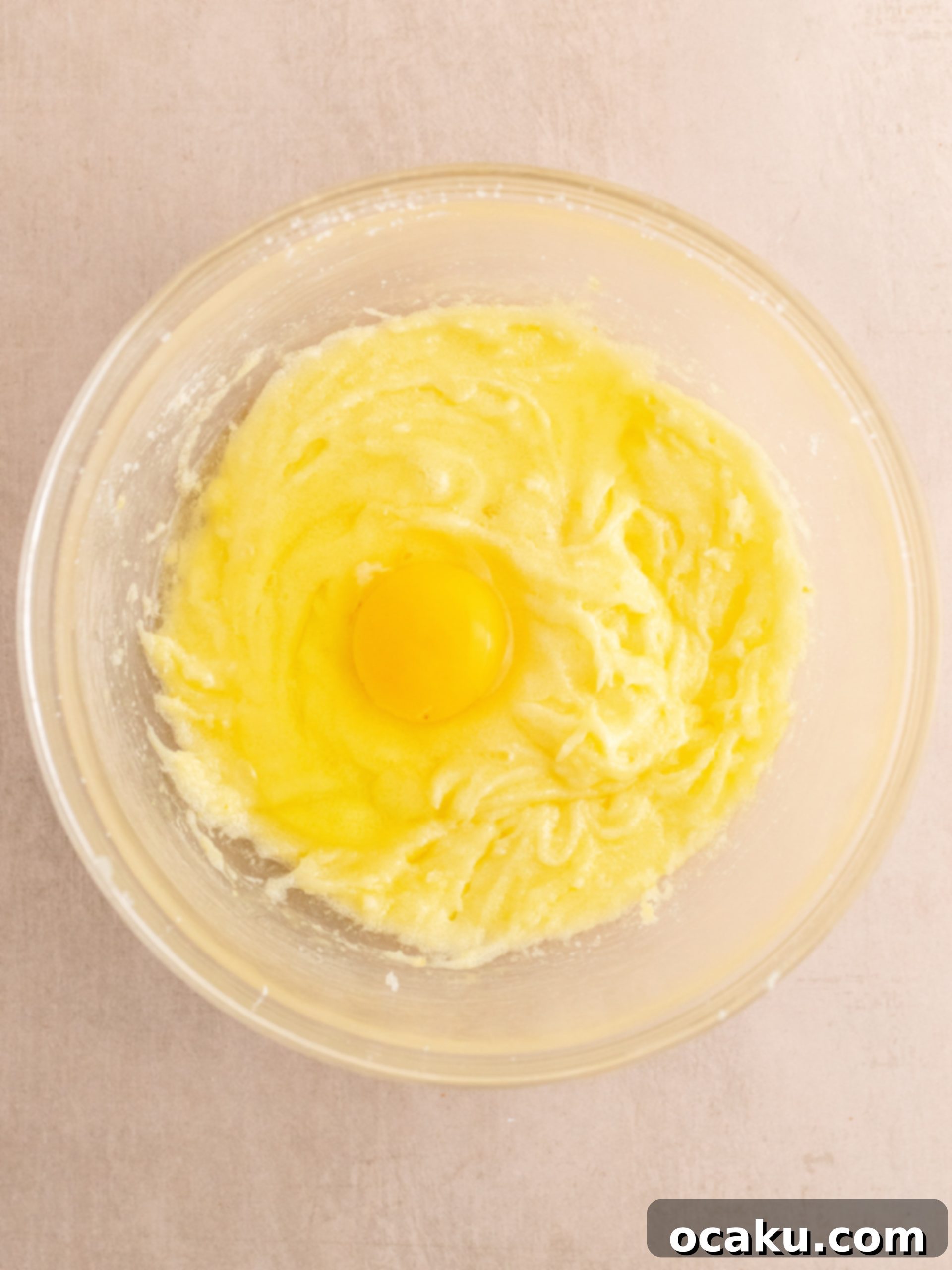 Eggs being added one by one to the creamed butter and sugar mixture.
