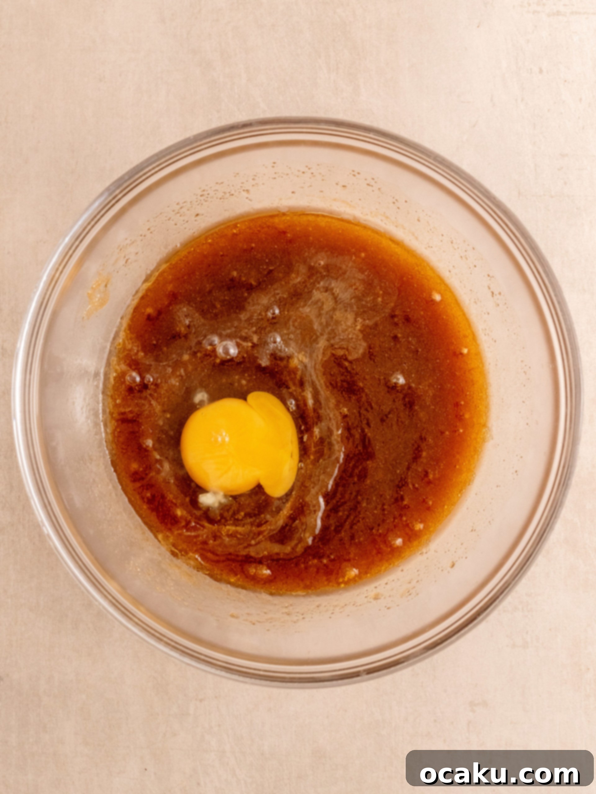 Mixing wet ingredients: melted butter, sugars, egg, and vanilla extract for cookie dough.