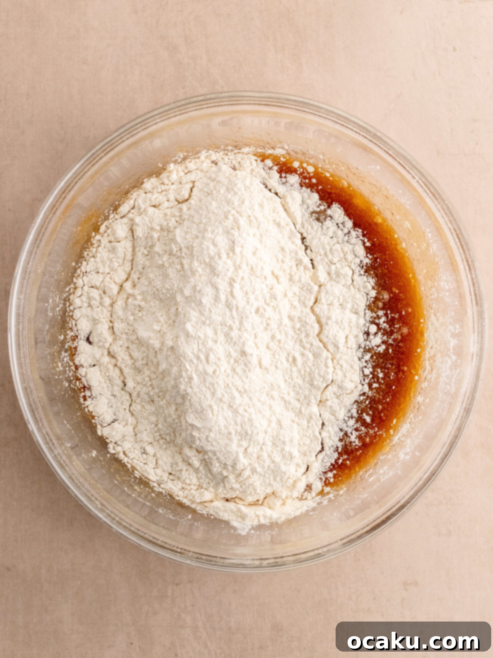 Adding dry ingredients to wet mixture and folding with a spatula for Oreo Chocolate Chip Cookies.