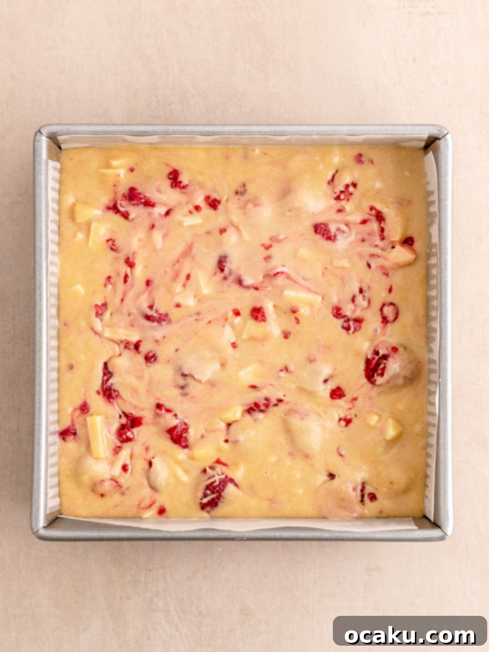 Step-by-step image of folding raspberries and white chocolate into batter