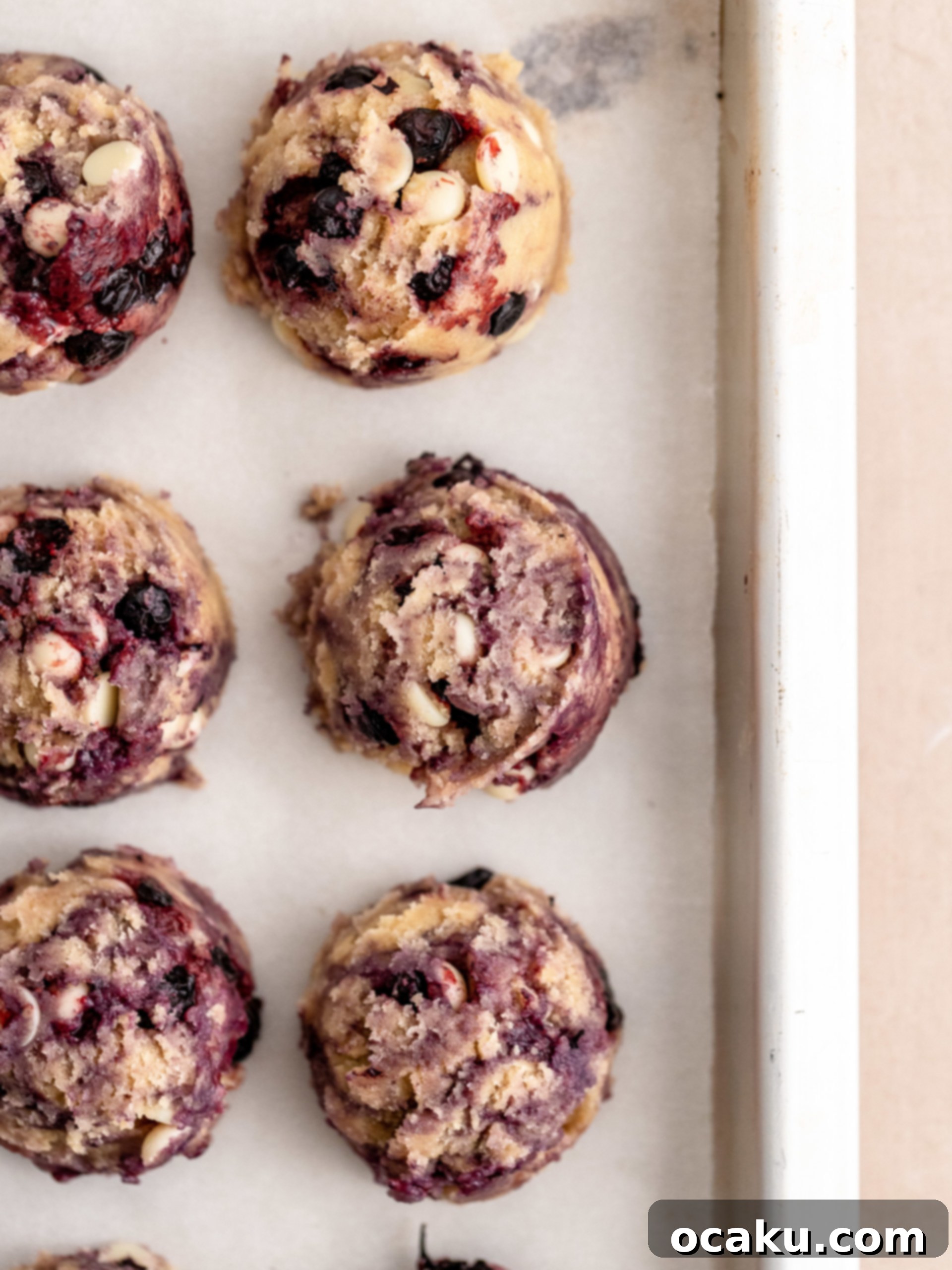 Freshly baked Lemon Blueberry Cookies on a baking sheet, with golden edges and a hint of purple from the blueberries.