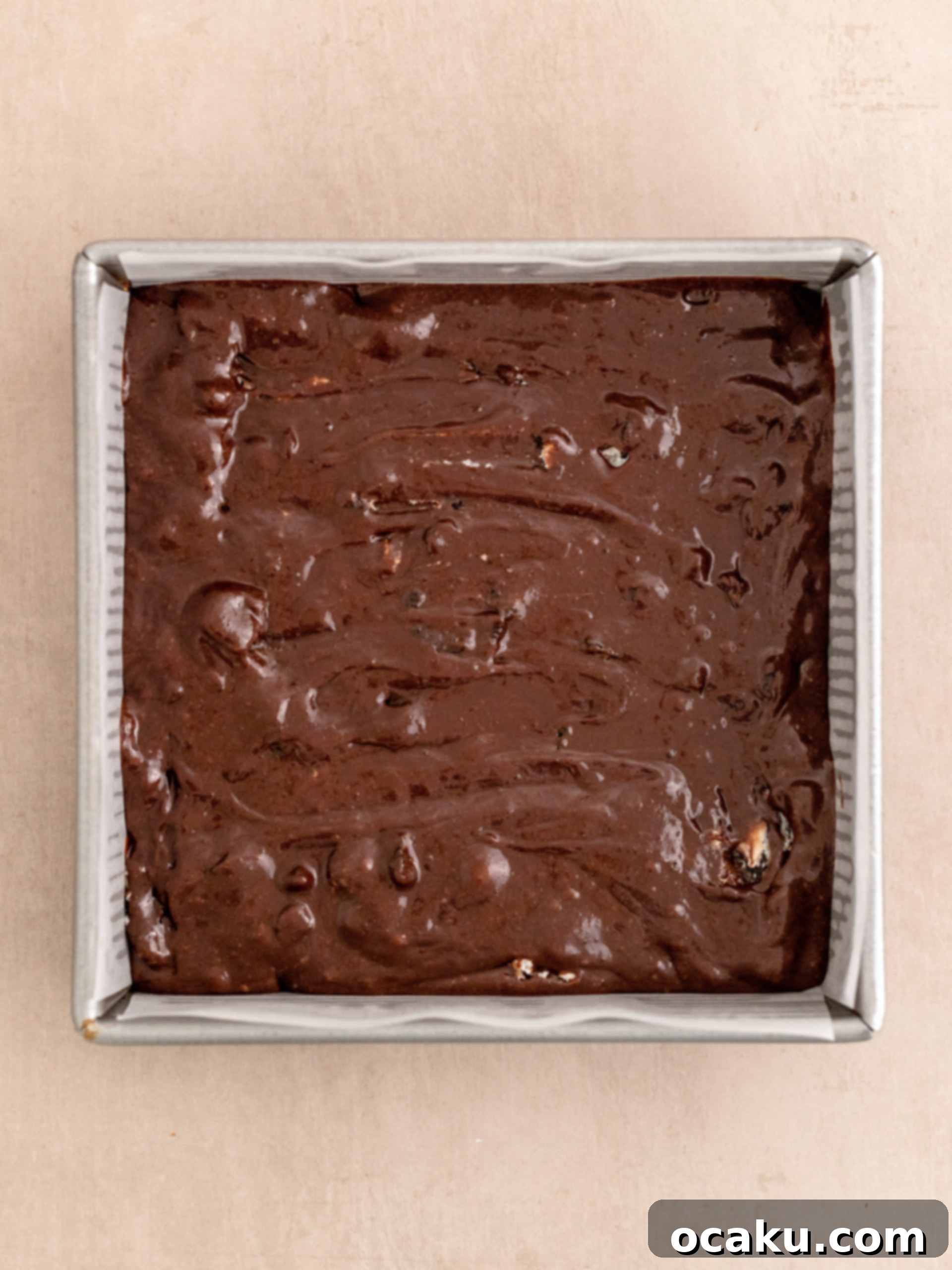 Pouring brownie batter into the prepared baking pan.