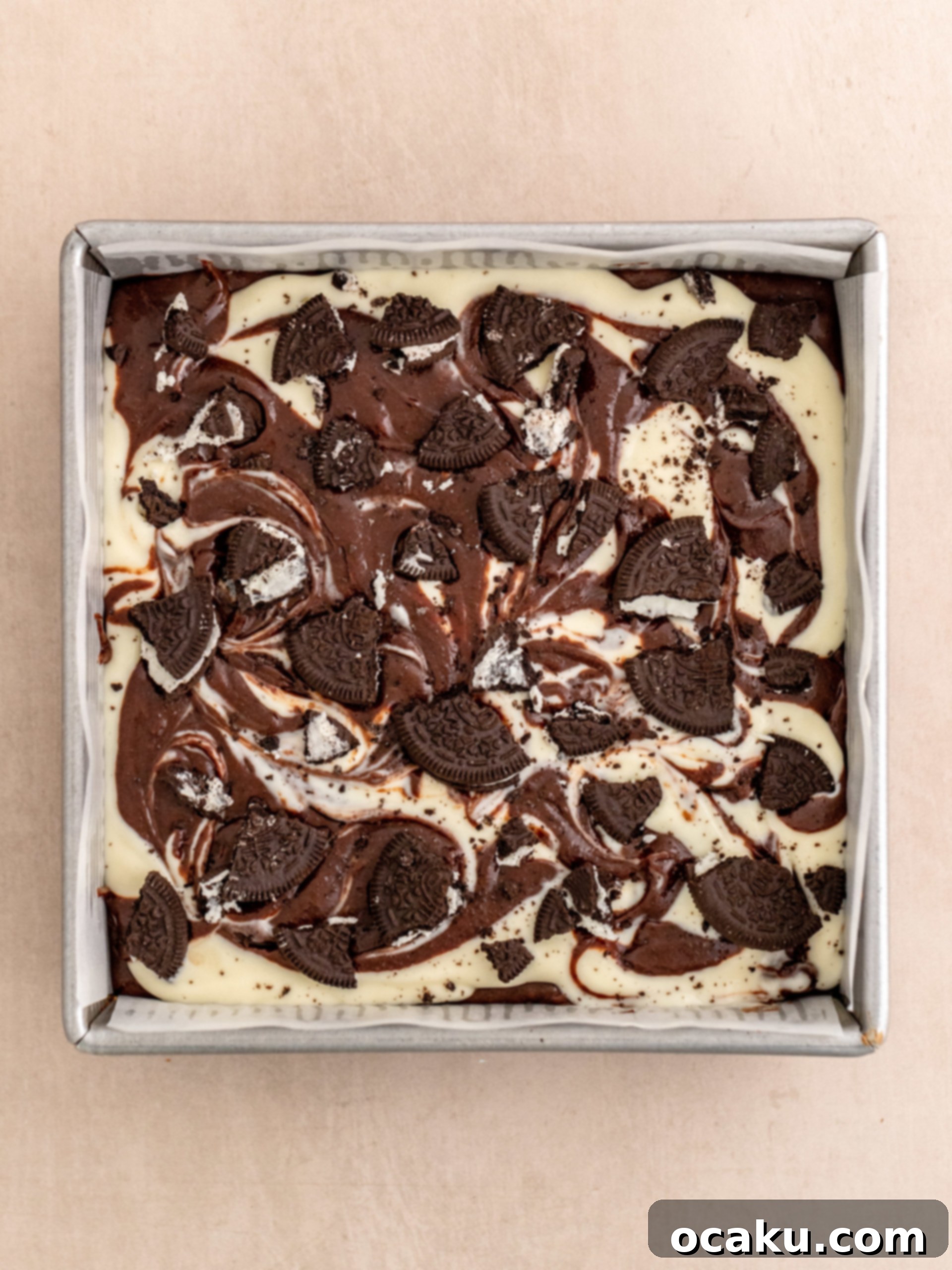 Swirling the brownie and cheesecake batters together with a toothpick and topping with more Oreos.