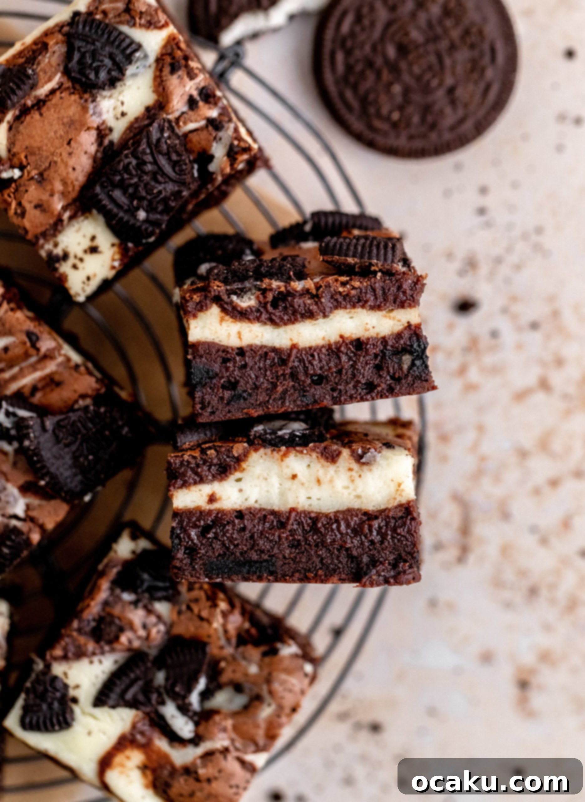 Three slices of Oreo Cheesecake Brownie, stacked on a plate, showing the thick fudgy brownie, creamy cheesecake swirl, and Oreo pieces.