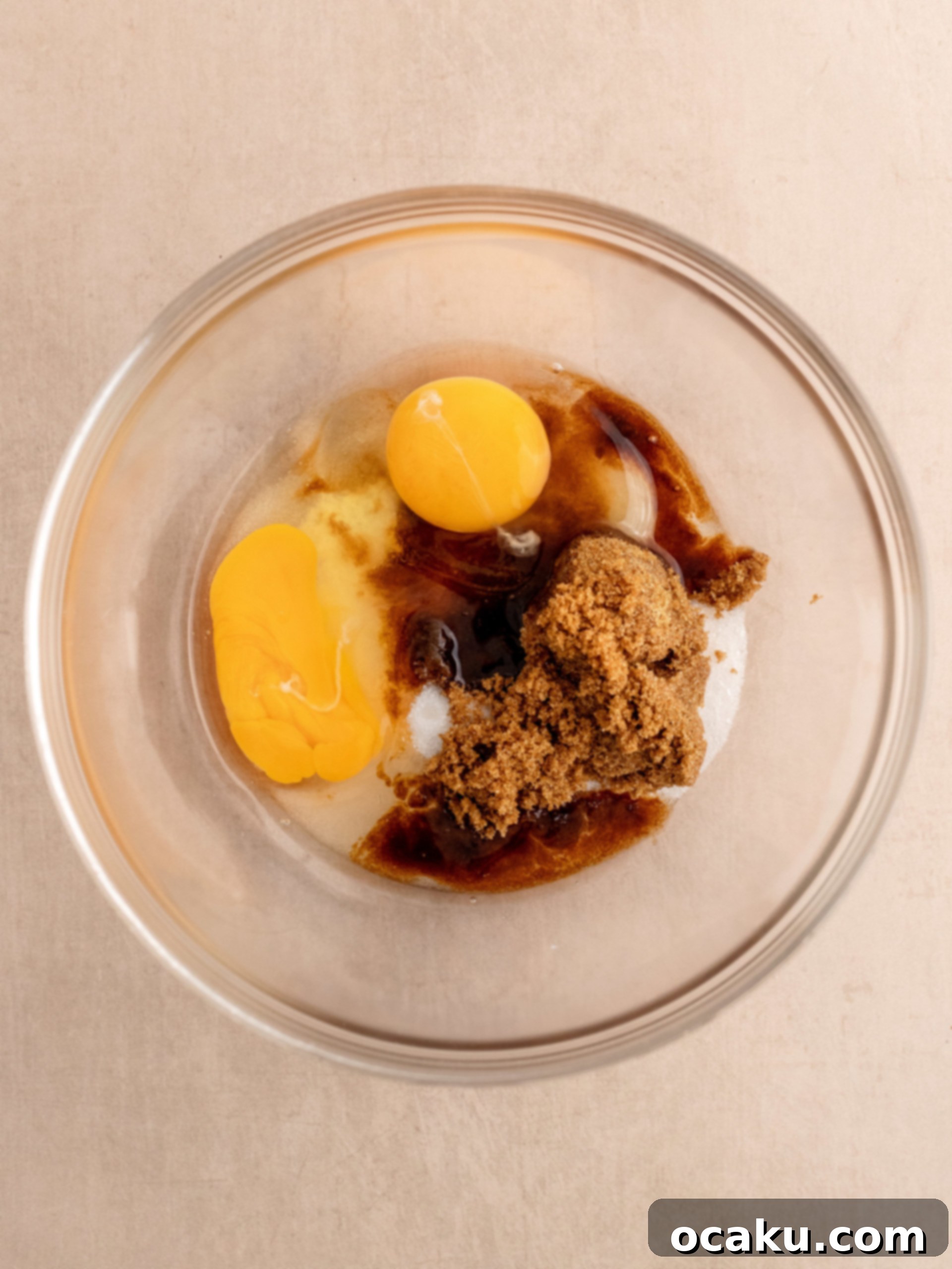 Eggs, granulated sugar, and brown sugar being whisked in a stand mixer bowl.