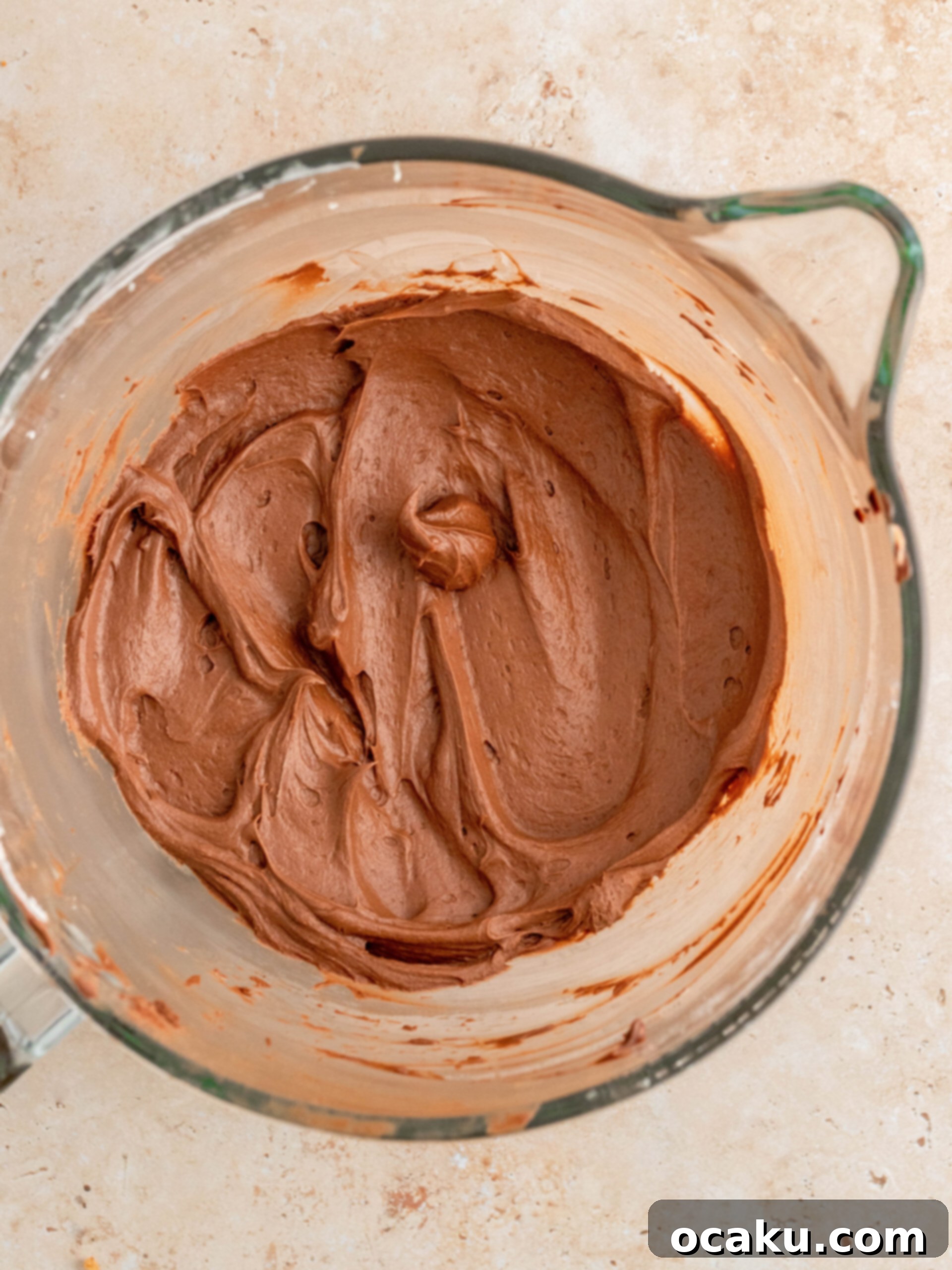 Chocolate ganache mixture being poured into buttercream