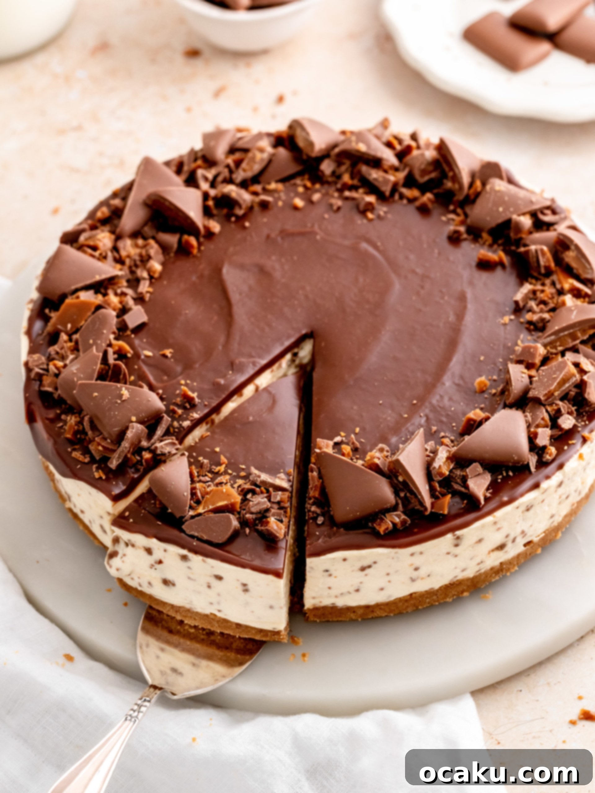 A stunning slice of No-Bake Daim Cheesecake, showing the crunchy base, creamy filling, and chocolate ganache topping with Daim pieces.