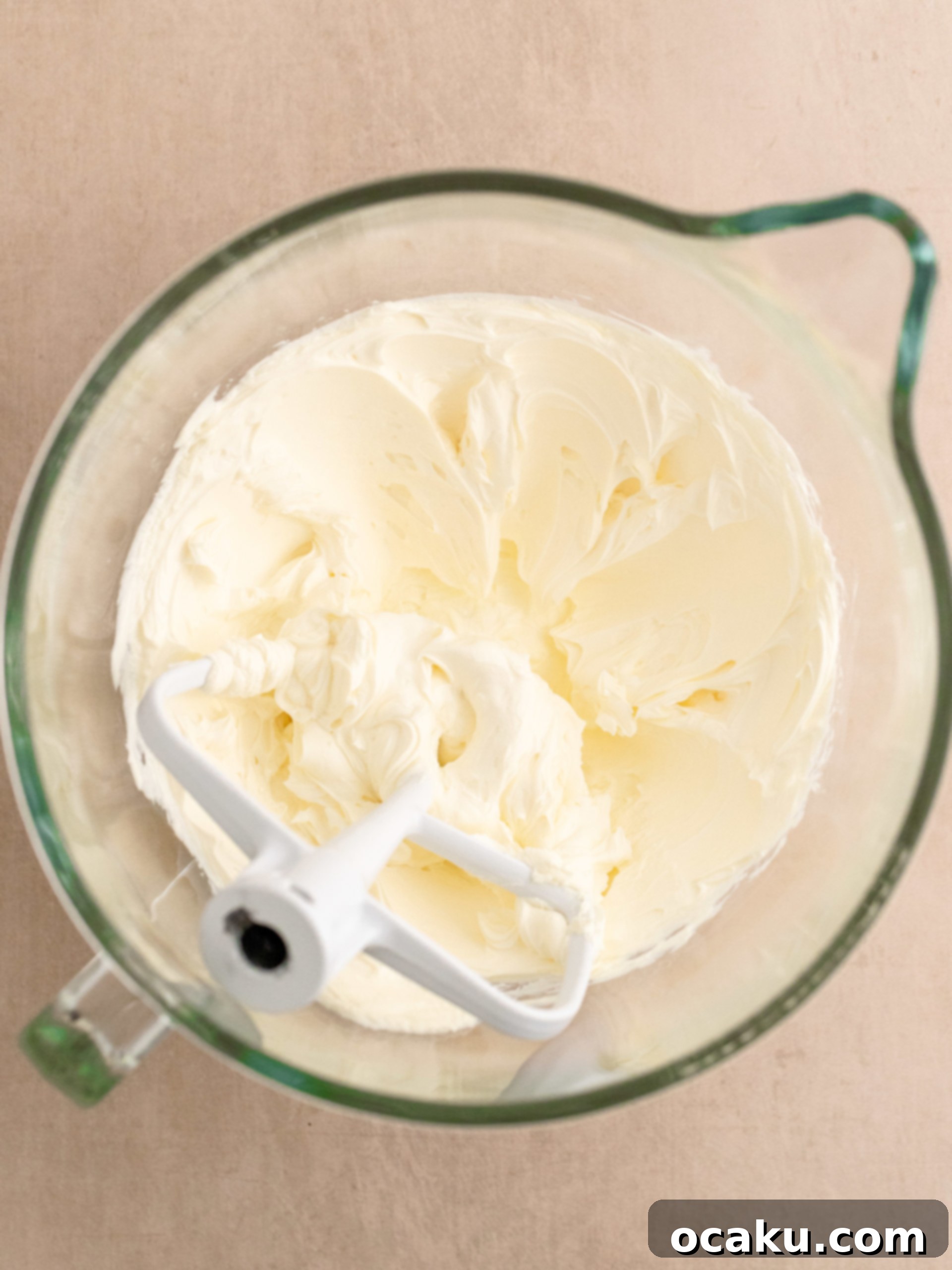 Cream cheese being mixed in a stand mixer.
